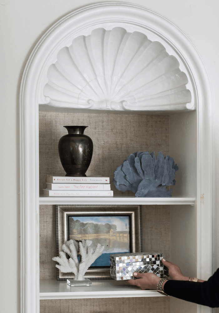 Built-in shelf styled with books, artwork, coral, sculptural objects, and mixed materials styled by JKB Home Design in Palos Verdes