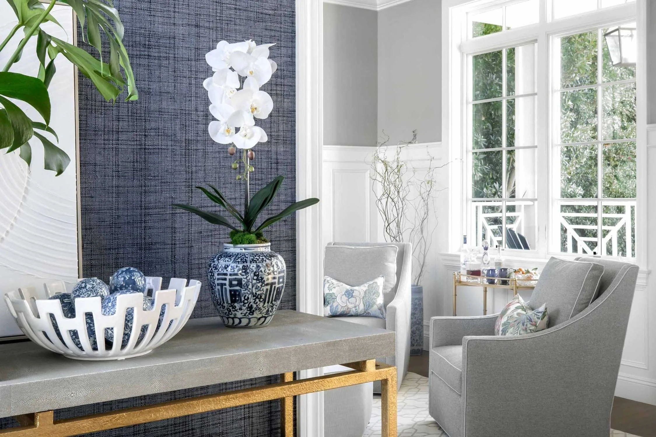 Blue wallpaper entry with orchids and ceramic decor, designed by JKB Home Design in Pacific Palisades