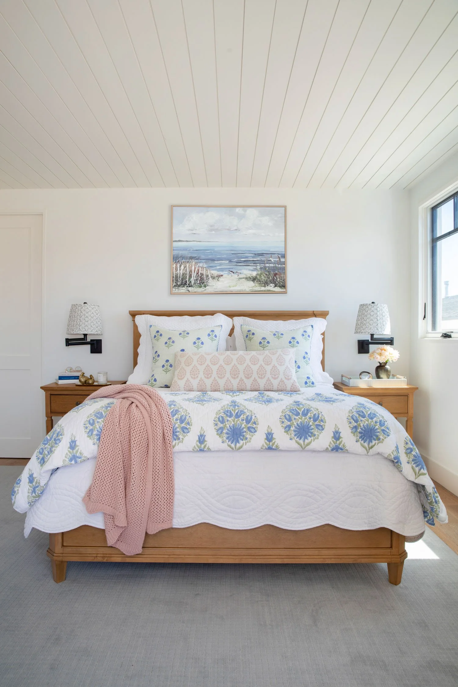 Light-filled Manhattan Beach bedroom with blue floral bedding, pink accents, and warm wood furnishings, designed by Julie Beuerlein
