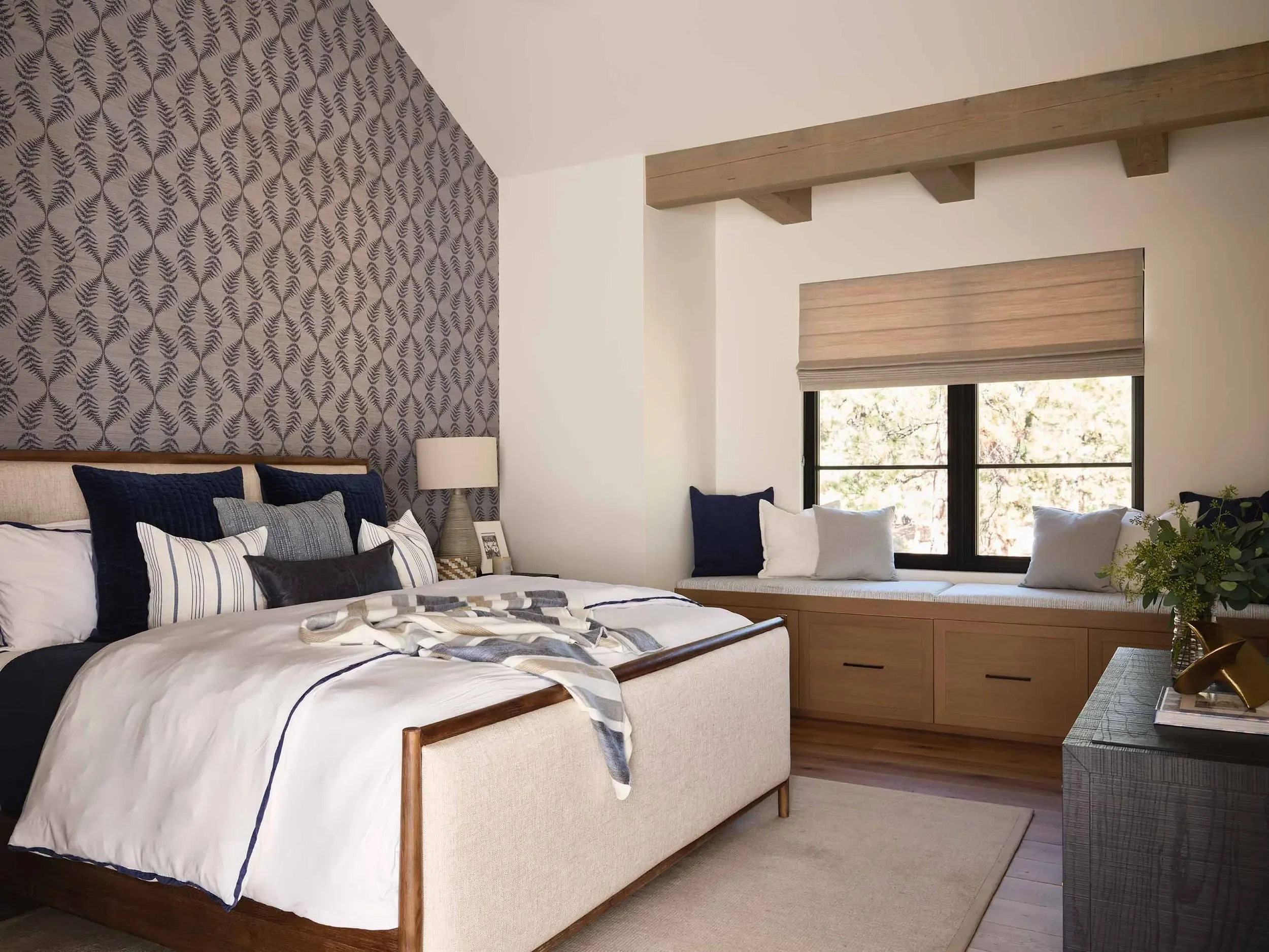 Bedroom with patterned wallpaper and window bench seating, designed by Julie Beuerlein, interior designer