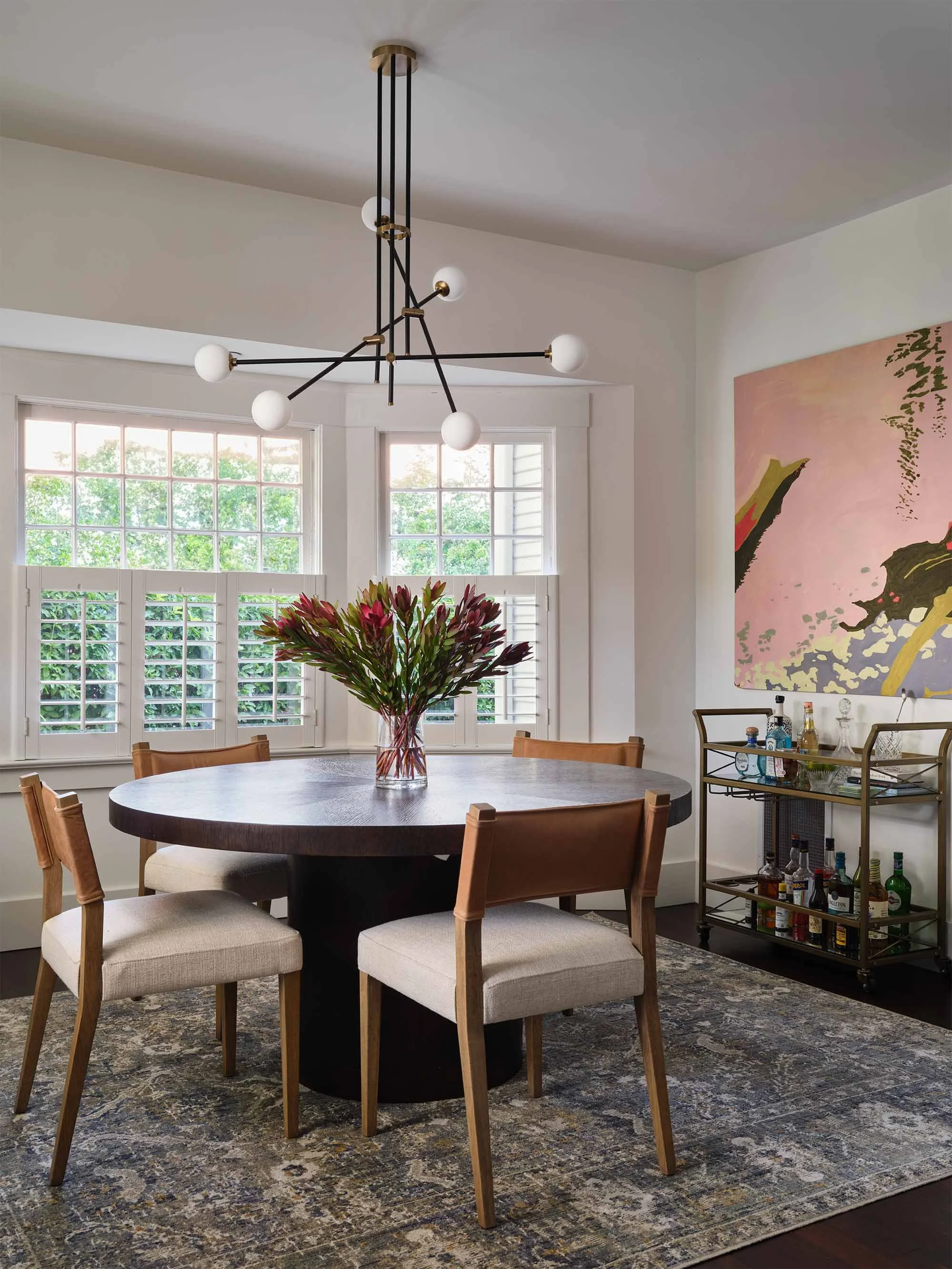 Dining space with sputnik chandelier and colorful artwork, designed by JKB Home Design