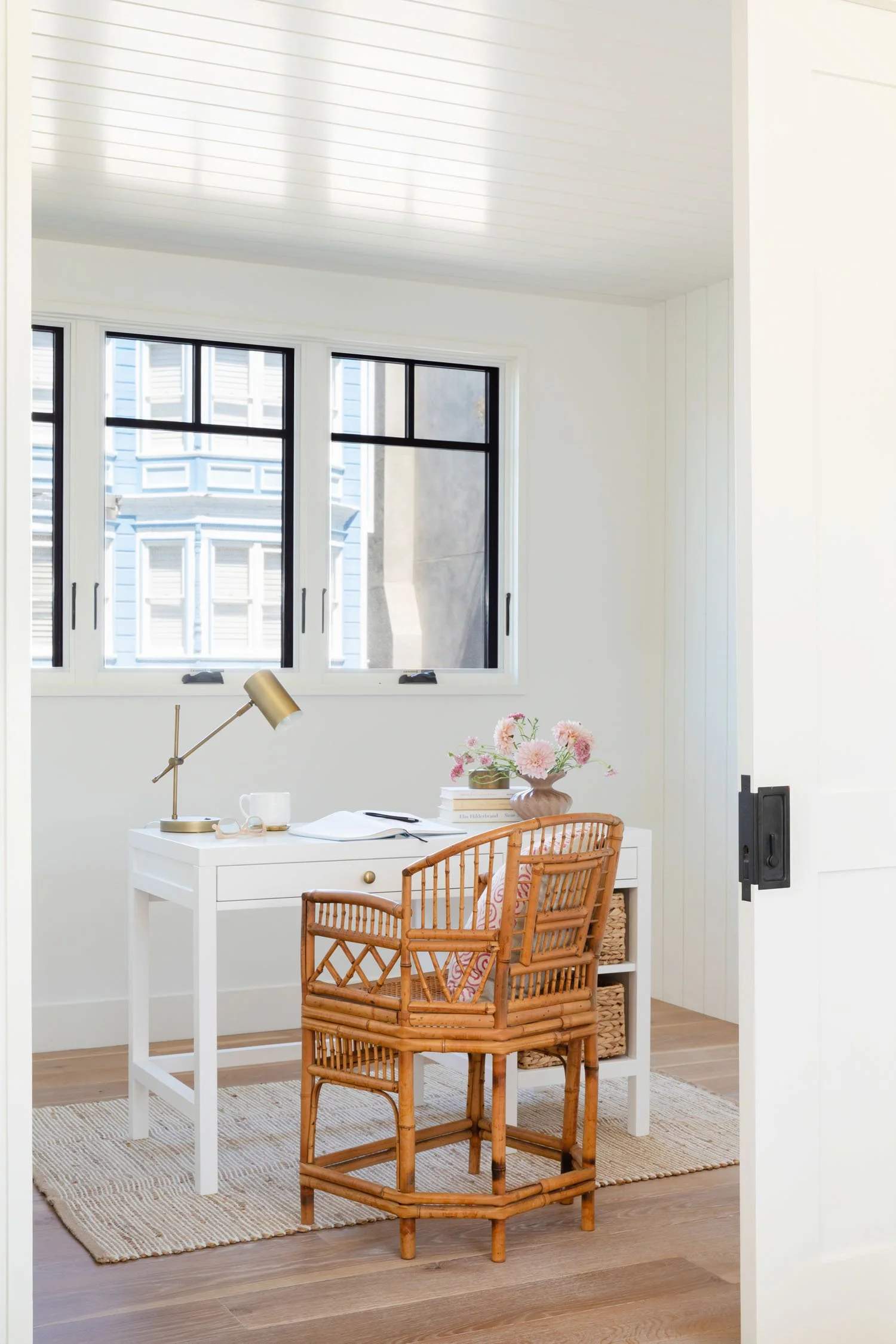 Bright Manhattan Beach home office with white desk, rattan chair, and coastal-inspired styling by Julie Beuerlein