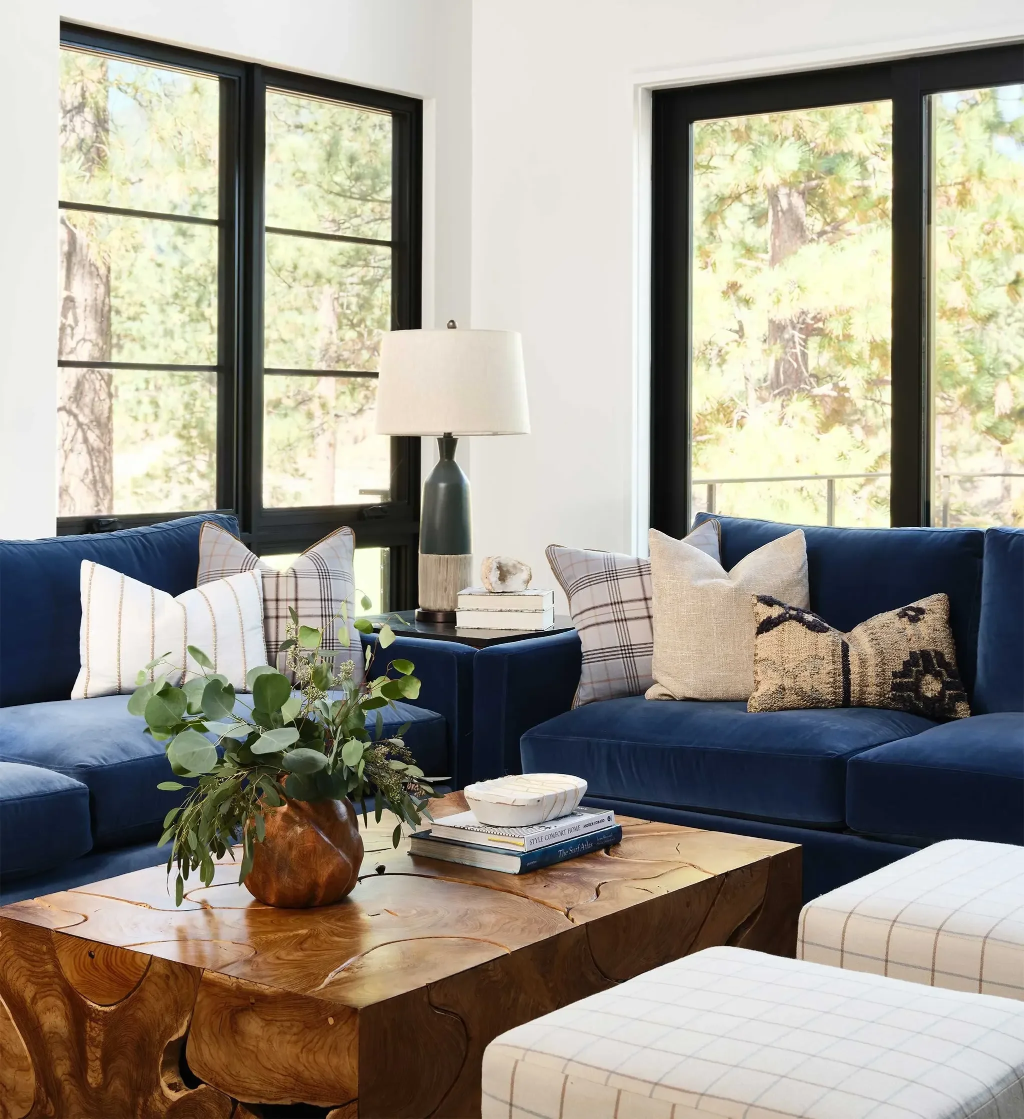 Calm mountain living room with blue sofas, natural wood coffee table, and forest views in Clear Creek Tahoe by Julie Beuerlein