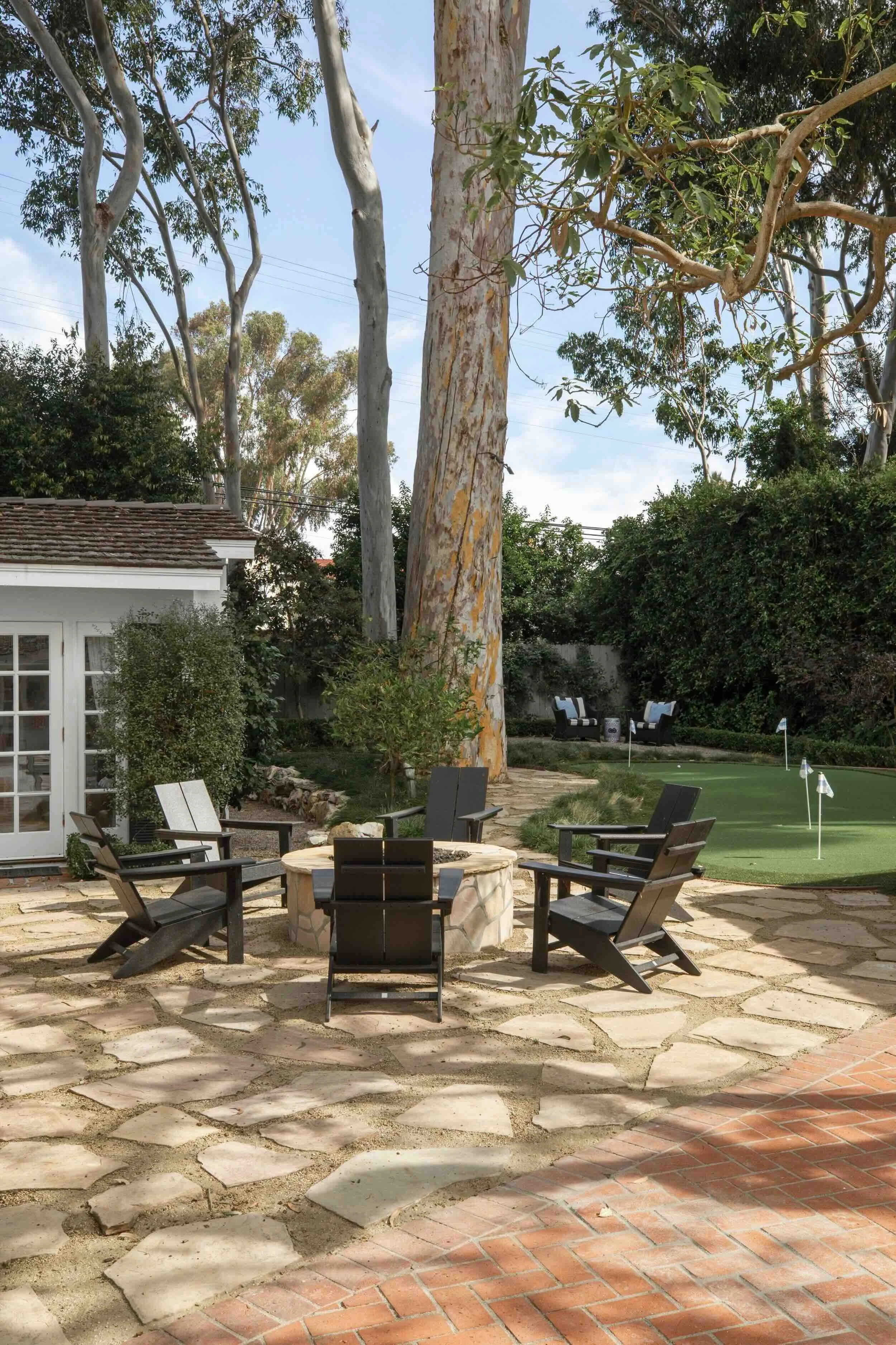 Palos Verdes Estates backyard with stone fire pit, Adirondack chairs, and putting green, designed by JKB Home Design