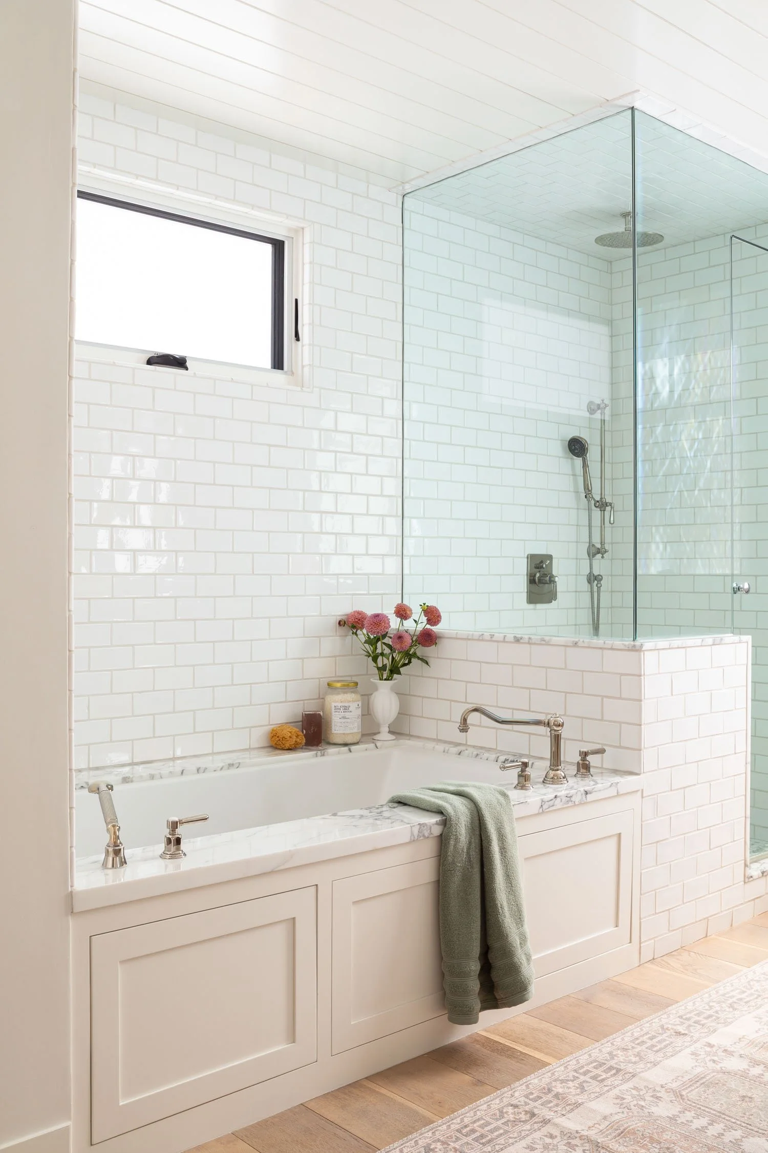 Light-filled Manhattan Beach bathroom with tiled soaking tub and glass-enclosed shower, designed by Julie Beuerlein