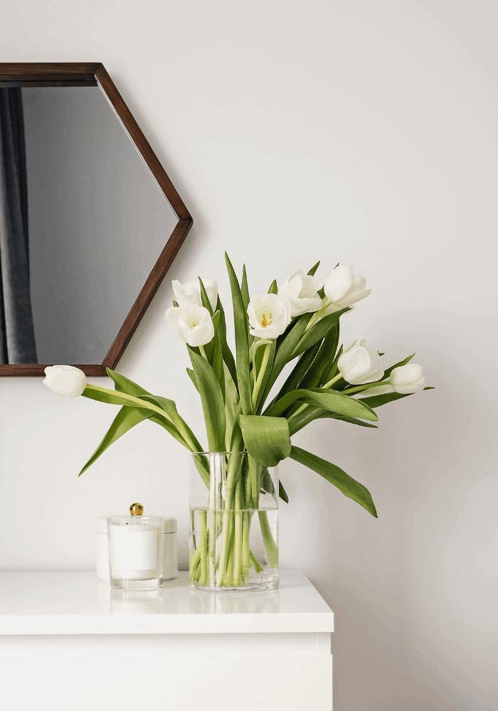White tulips and candles styled on a dresser for a simple spring home refresh by JKB Home Design in Southern California home