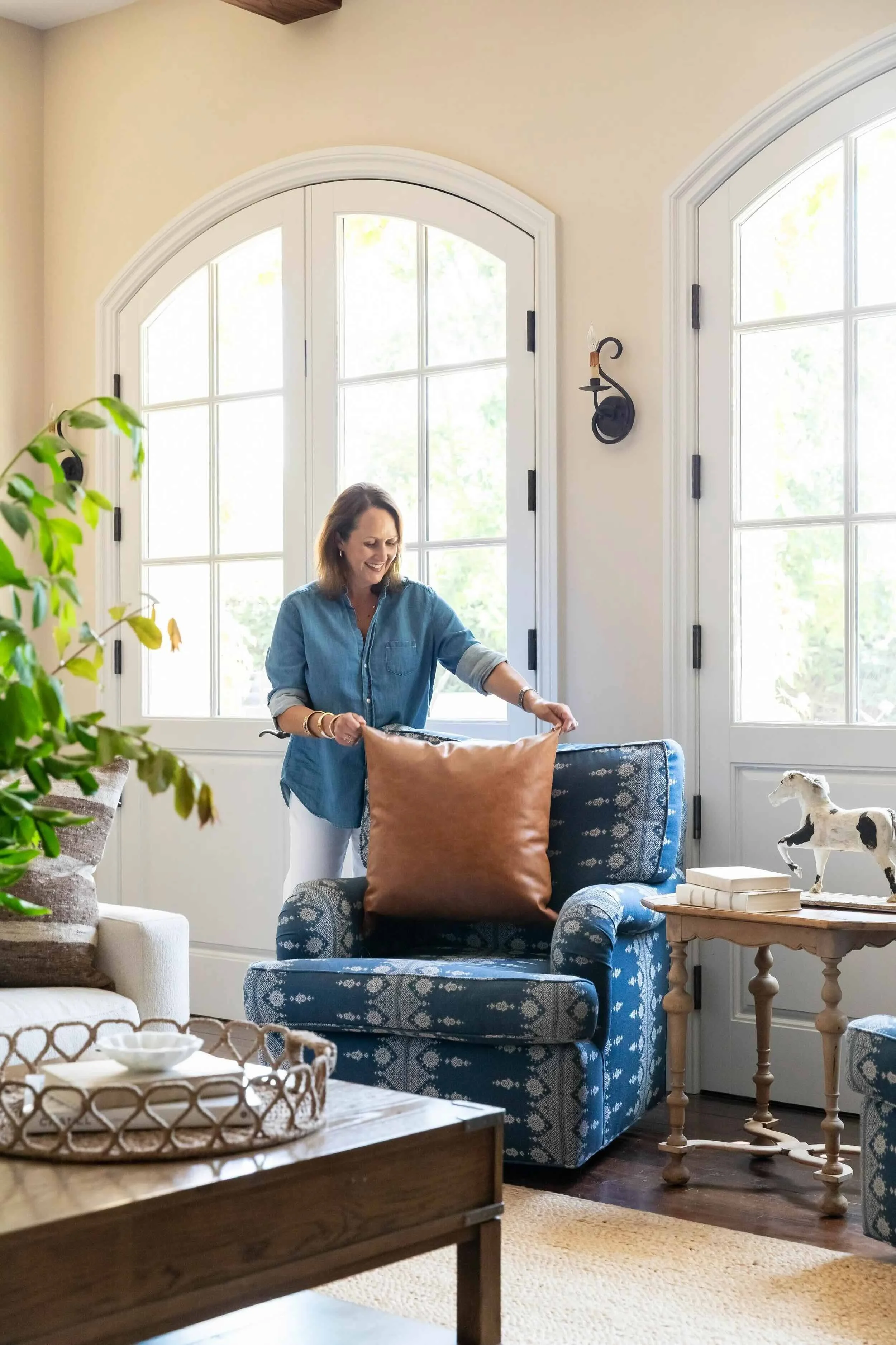 Interior designer Julie Beuerlein styling a blue armchair in a thoughtfully layered living room