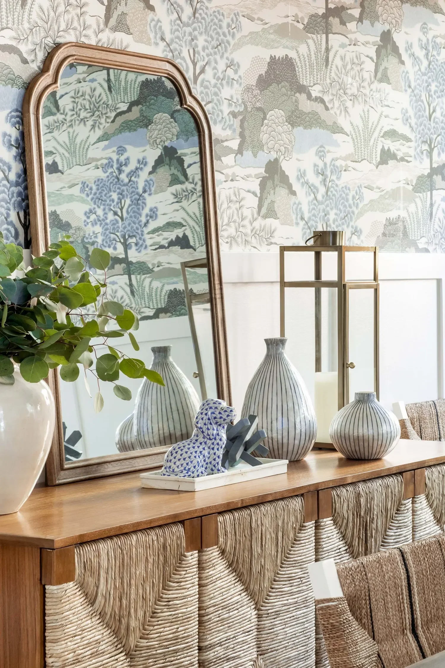Dining room console with woven detailing, decorative mirror, and botanical wallpaper in Palos Verdes Estates by JKB Home Design