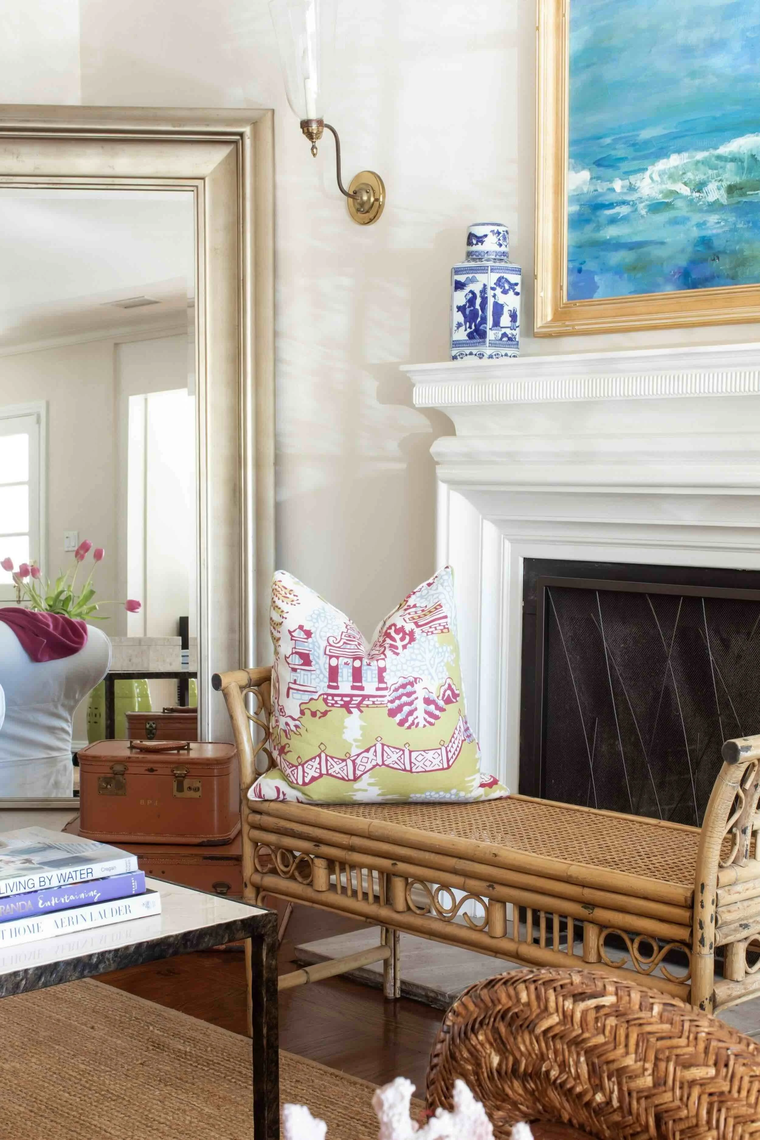 Rattan bench with colorful patterned pillow beside a traditional fireplace, styled by JKB Home Design