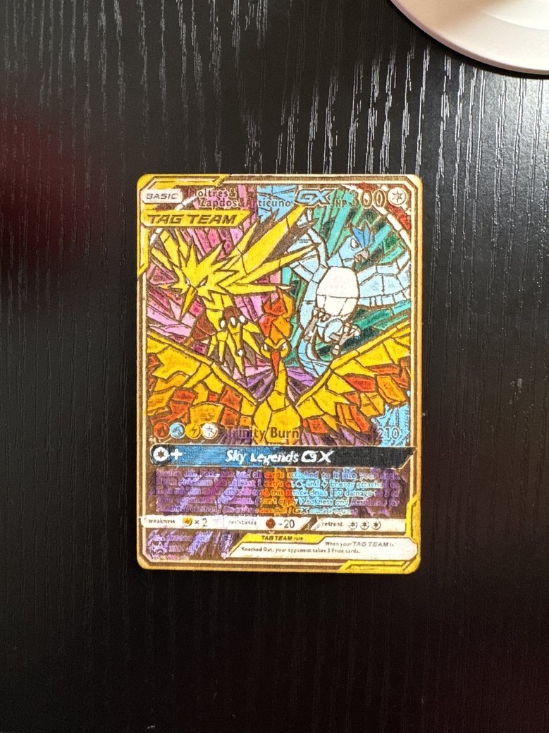A Pokémon trading card featuring a colorful illustration of a Charizard with a rainbow background, labeled as a Tag Team GX card, with various stats and descriptions.