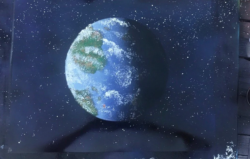 A model of Earth in space surrounded by stars, positioned on a black surface with shadows.