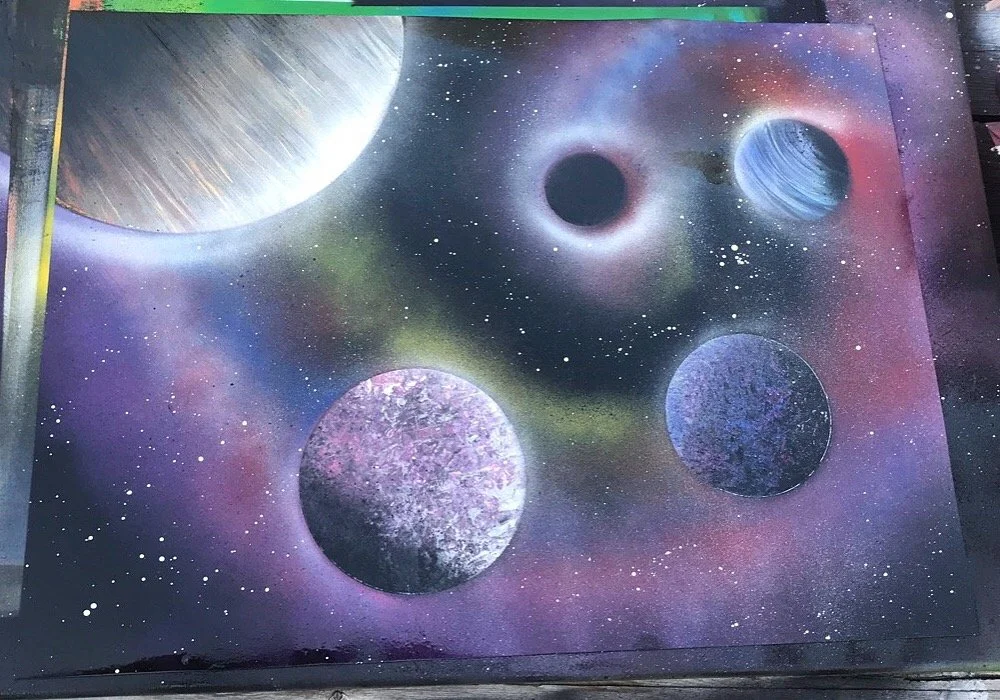 A colorful spray-painted mural of outer space with five planets and a starry background.