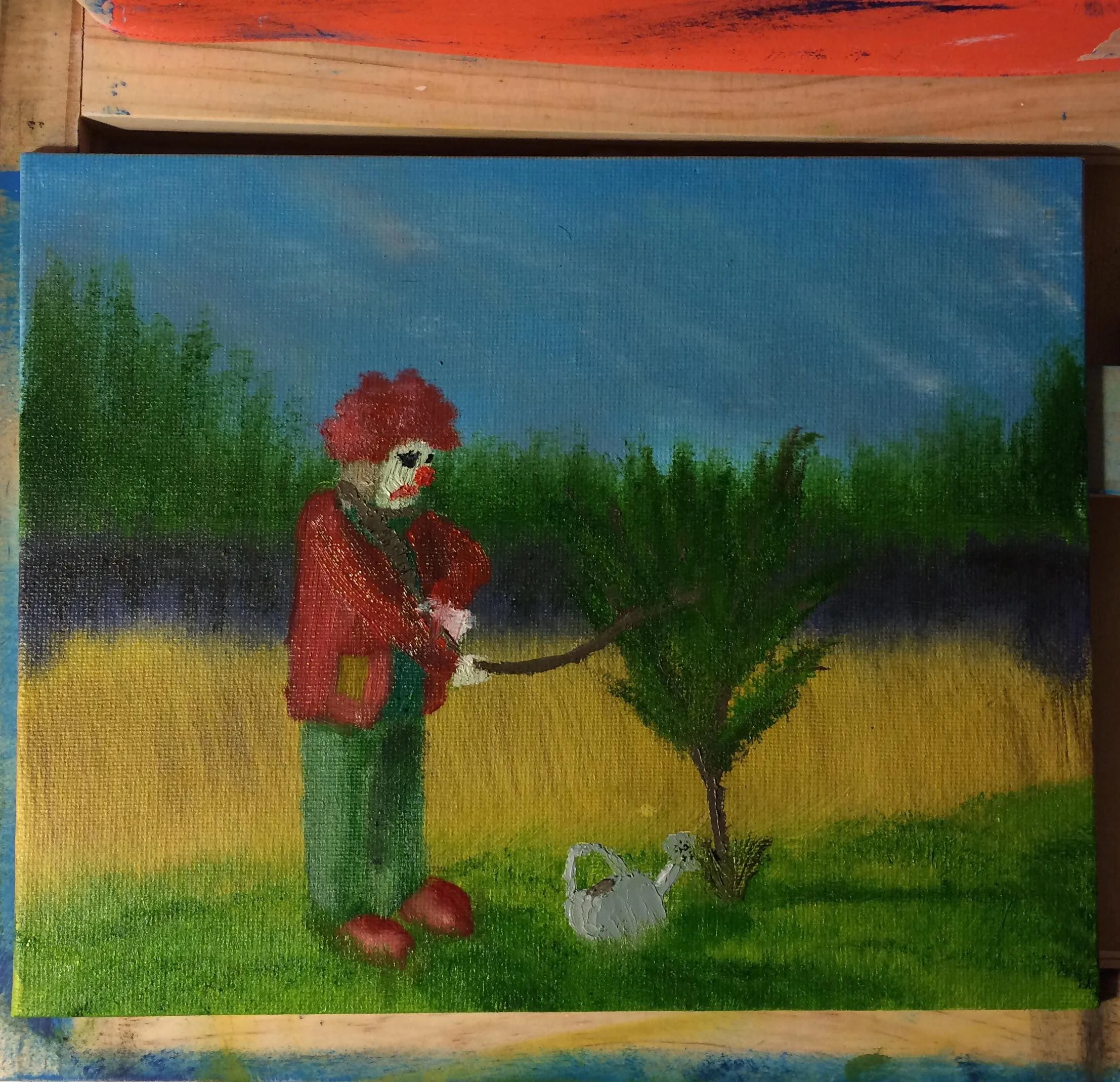 A colorful painting of a clown with red hair, a white face, and red nose, wearing a red jacket and green pants, standing outdoors next to a small tree. The clown is holding a branch of the tree, and there is a white duck sitting on the grass nearby. 