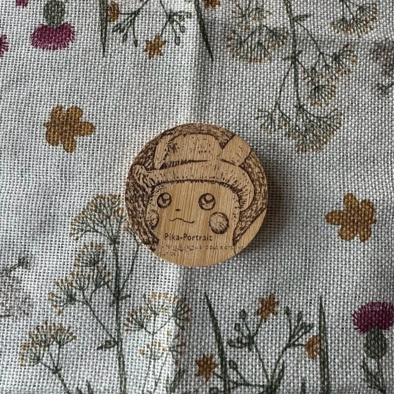 Wooden stamp with Pikachu character engraving placed on a fabric with floral pattern.