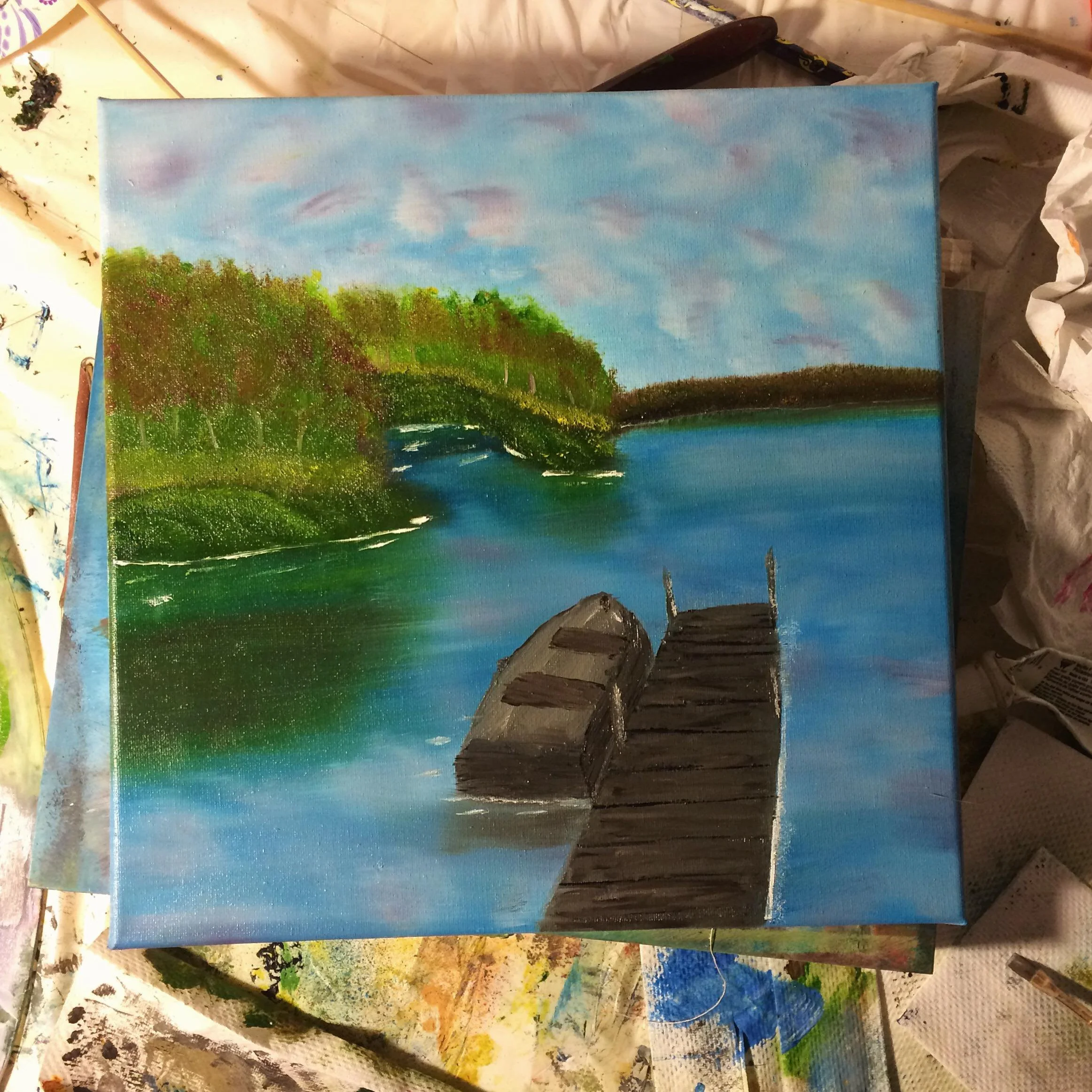 A peaceful landscape painting of a lake with a wooden dock and floating debris, lush green trees on the left, and a blue sky with soft clouds.