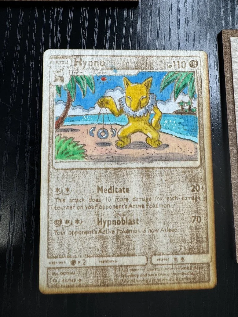 A custom illustrated Pokémon card featuring a feline creature with bright yellow fur and a bushy white mane, standing on a tropical beach with palm trees, ocean, and blue sky in the background. The card is titled 'Hypno' and has moves 'Meditate' and 