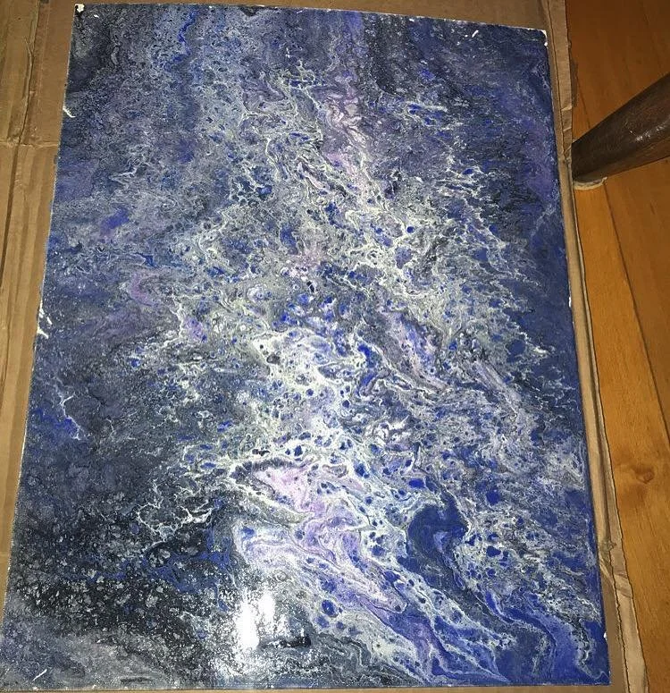 An abstract painting with swirling patterns in shades of blue, purple, black, and white, created with fluid acrylics.