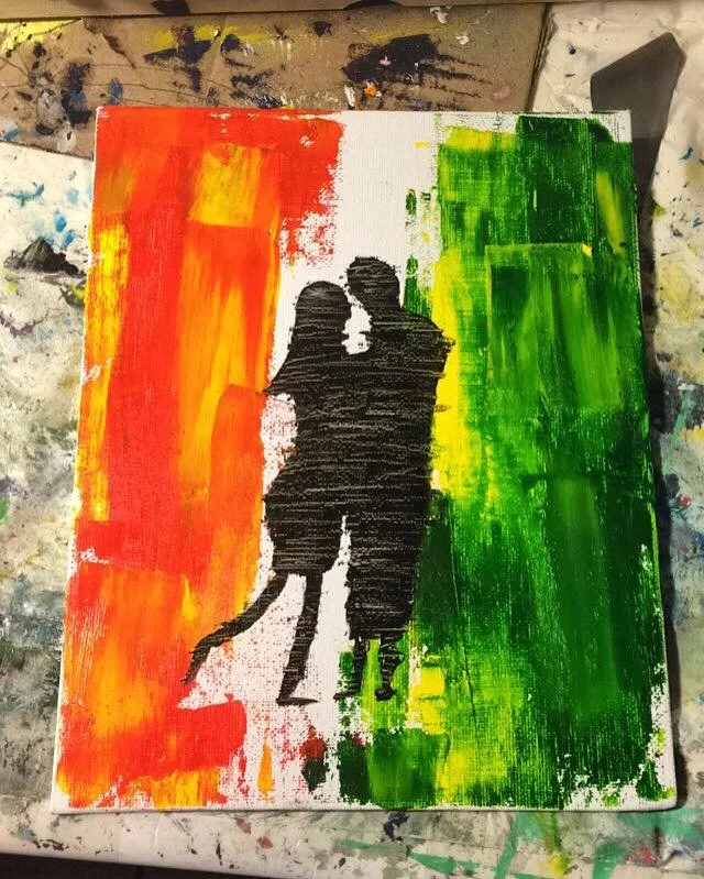A painting depicting a silhouette of a romantic couple walking together, with the background painted in the colors of the Rastafarian flag: red, yellow, and green.