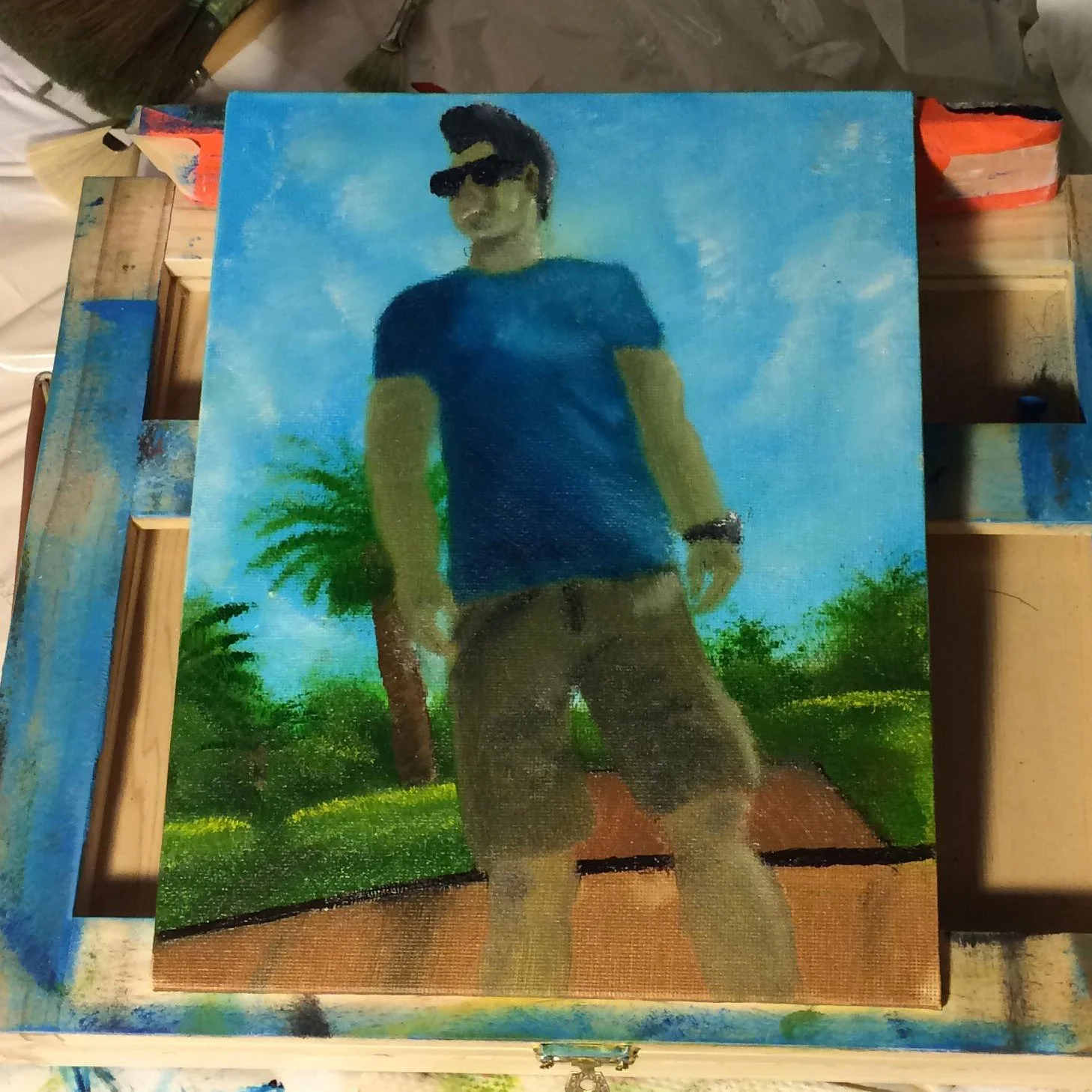 A painting of a young man wearing sunglasses, a blue t-shirt, and shorts, standing outdoors with palm trees and a blue sky in the background.