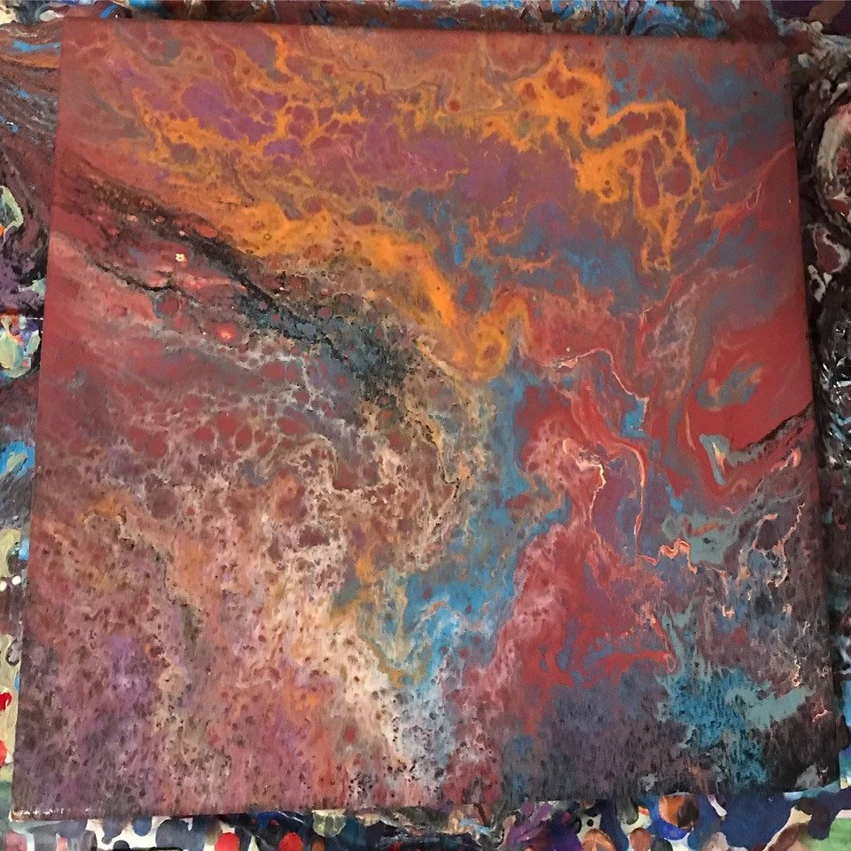 Abstract swirl of various colors including orange, red, purple, blue, black, and white in a fluid pattern