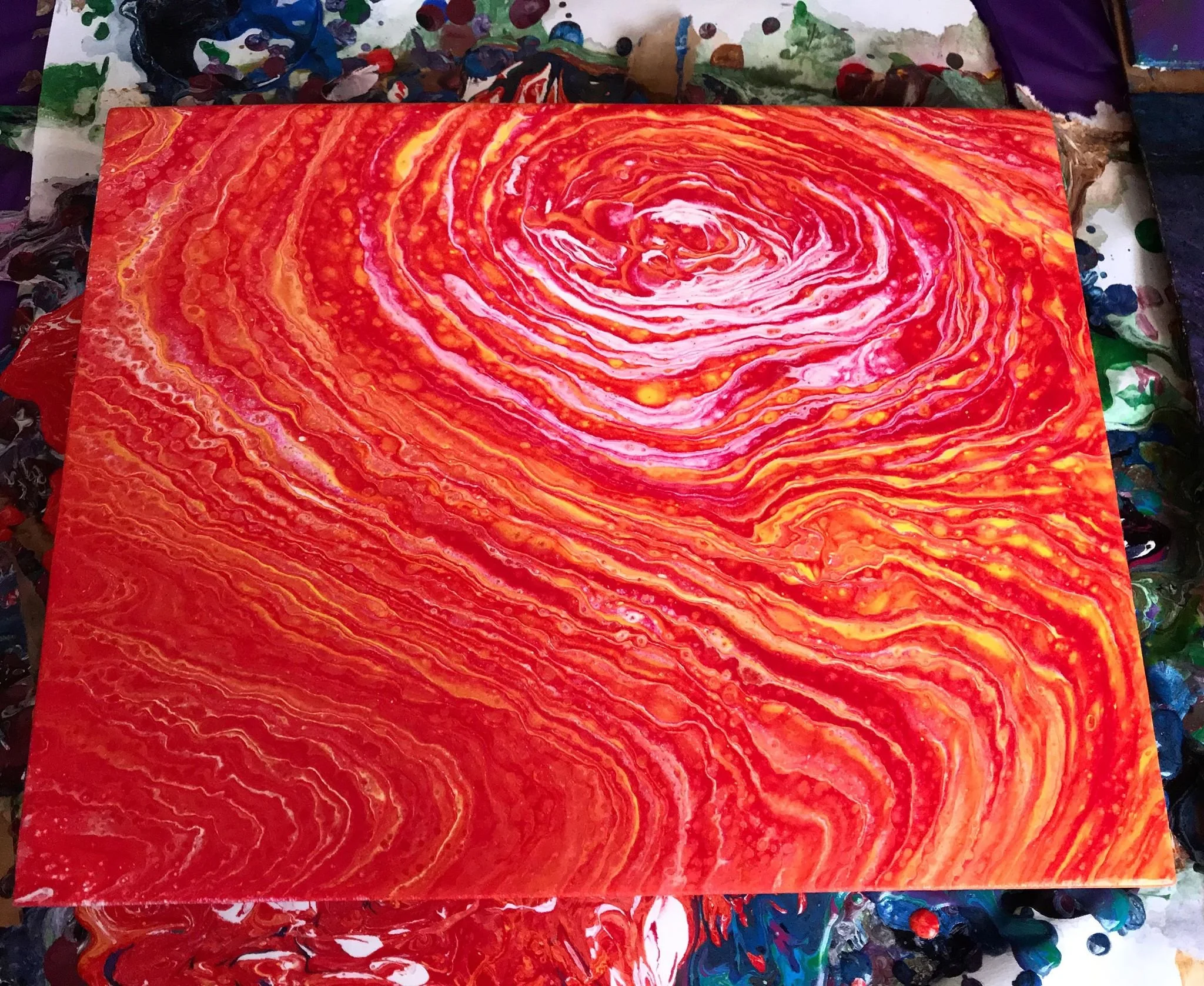 Abstract swirling painting in shades of red, orange, yellow, and white with a spiral pattern in the center.