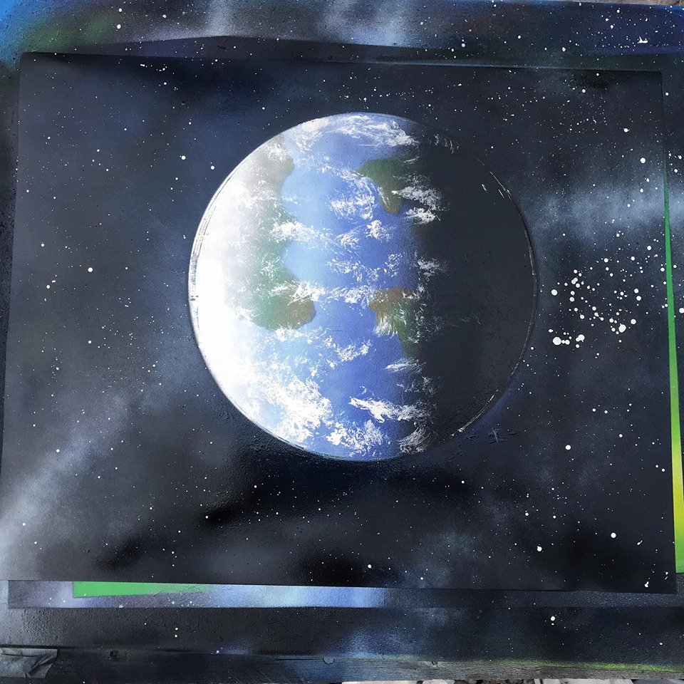 Street art mural of planet Earth with space stars in the background.