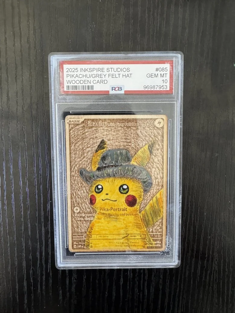 A trading card featuring Pikachu wearing a grey felt hat, with a yellow fur body and large eyes, encased in a plastic holder with a grading label at the top.