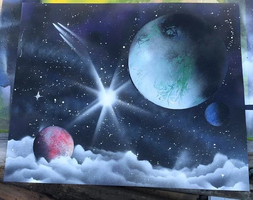 Space scene featuring three planets, one large with green terrain, one smaller and red, and another small and blue, set against a starry background with a bright star and clouds below.