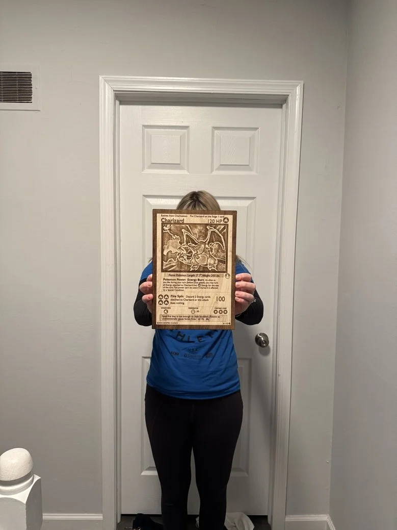 Person standing in front of a door holding a Charizard Pokémon card display.