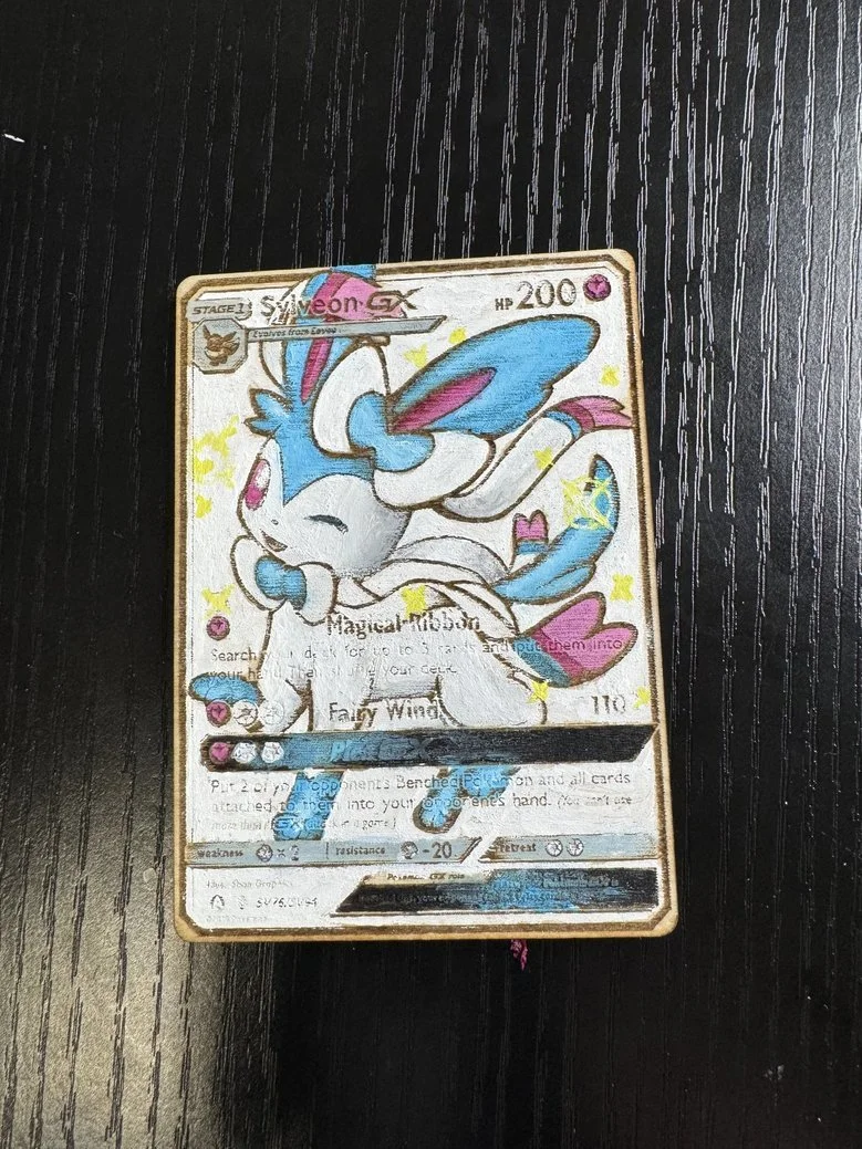 A trading card featuring a cartoon-style, blue and pink rabbit character with long ears and a fluffy tail, on a black textured surface.