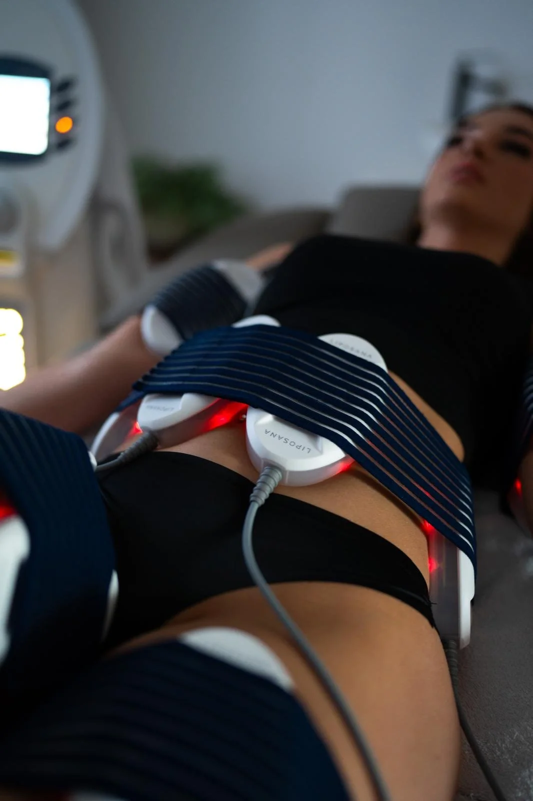 Woman undergoing a medical or therapeutic procedure using multiple sensors or electrodes attached to her abdomen, connected with wires to a machine.