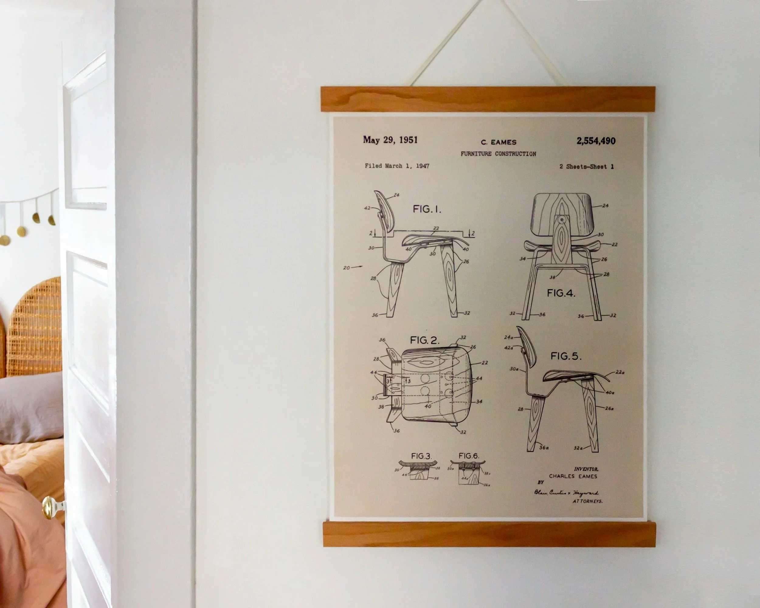 A vintage blueprint of a chair design with detailed technical drawings and annotations, mounted on a white wall in a room with natural light coming through windows.