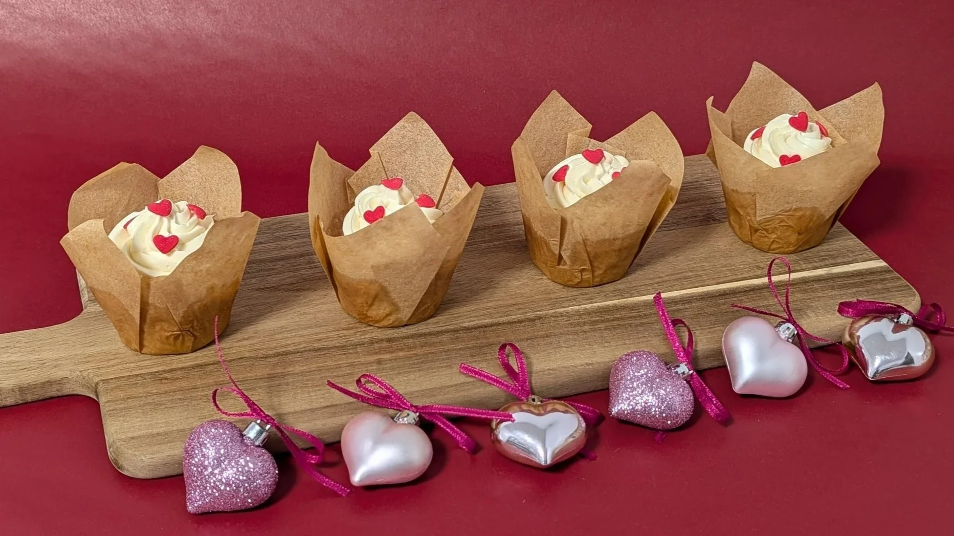 4 Strawberry cupcakes in a row on a cutting board