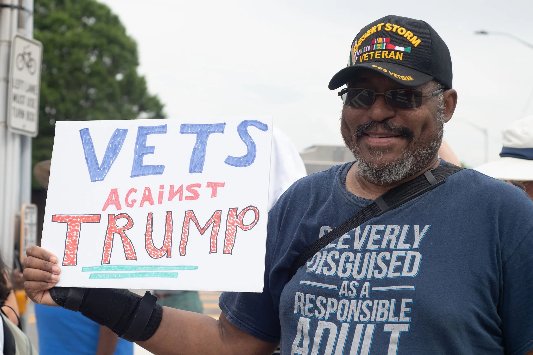 U.S. Military Veteran holds a sign that says "Vets Against Trump"