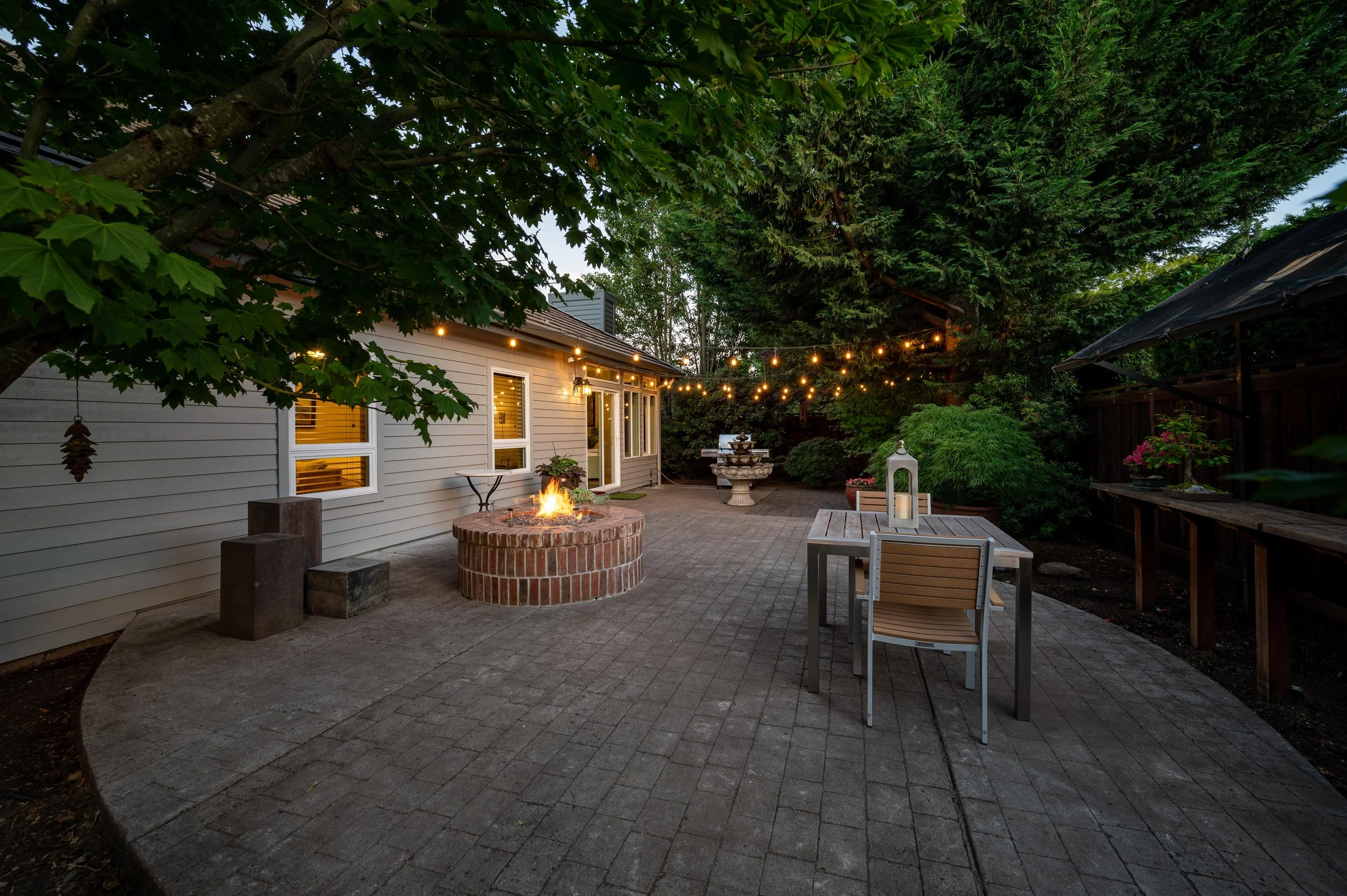 Outdoor patio with fire pit, seating area, and warm evening lighting