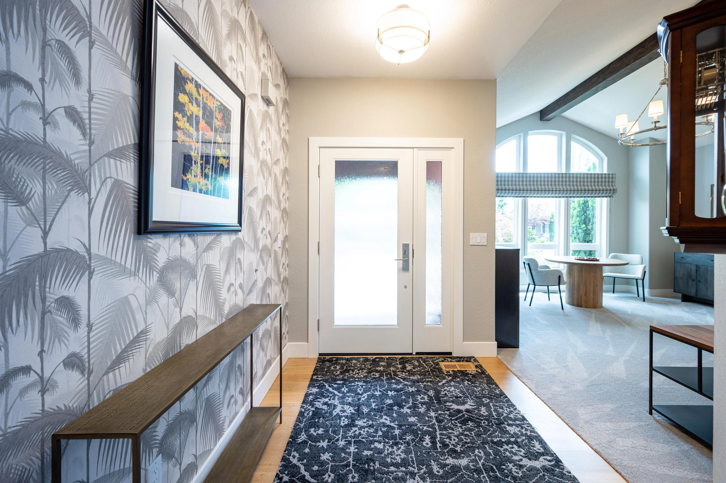 Entry hallway with patterned wallpaper, bench seating, and front door view