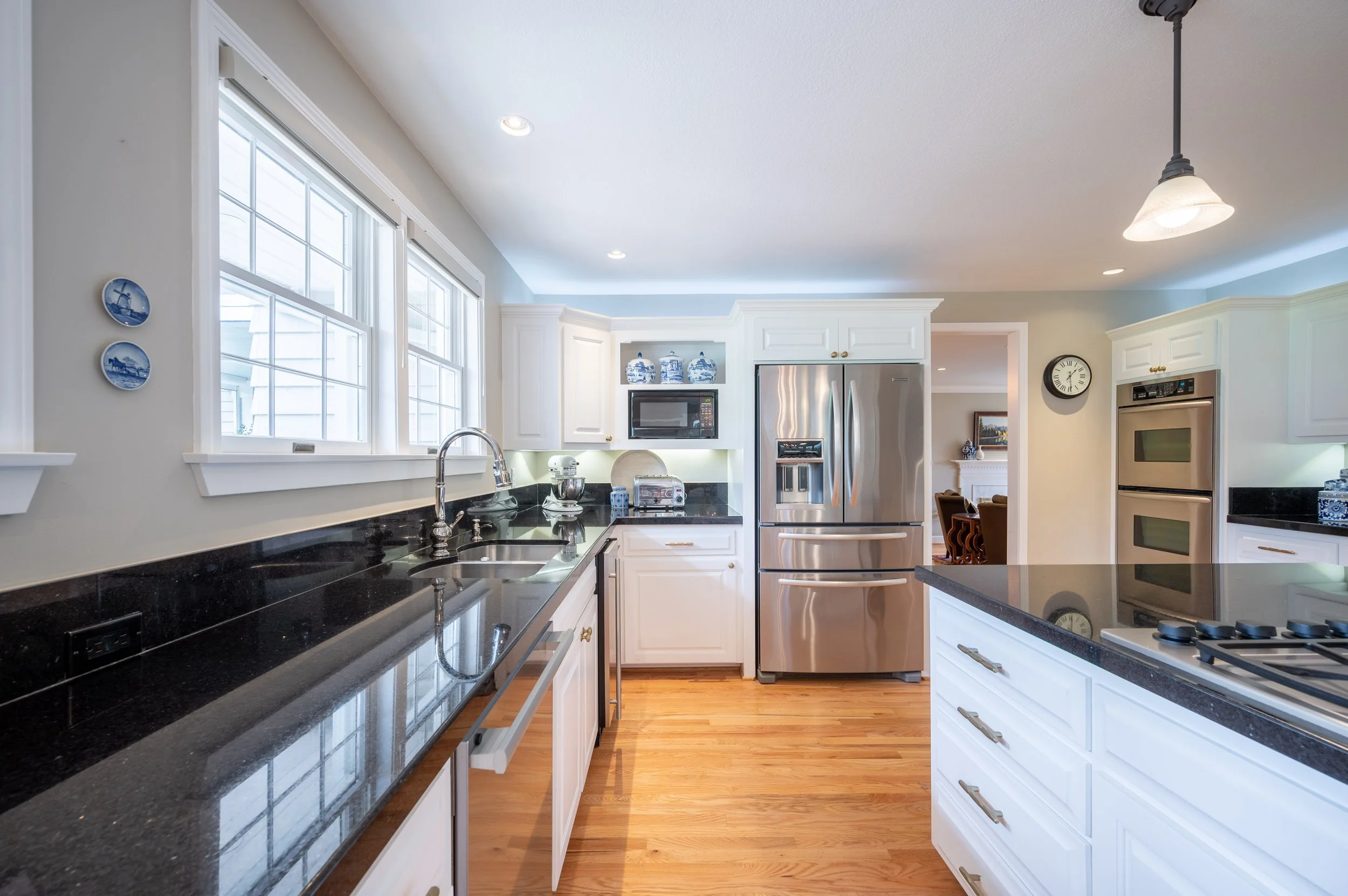 Kitchen with white cabinetry, stainless appliances, and wood floors