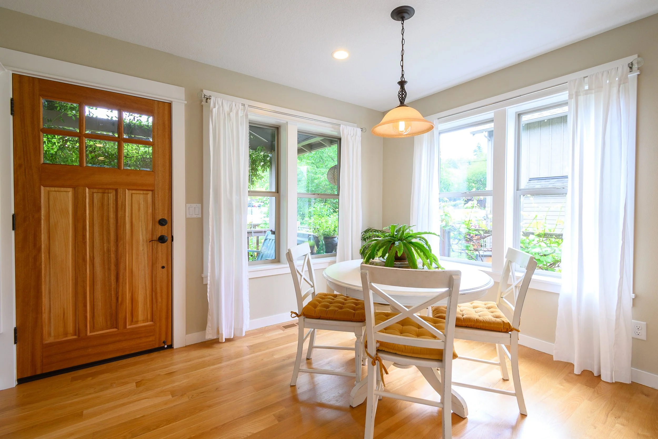 Breakfast nook with round table, wood floors, and large windows