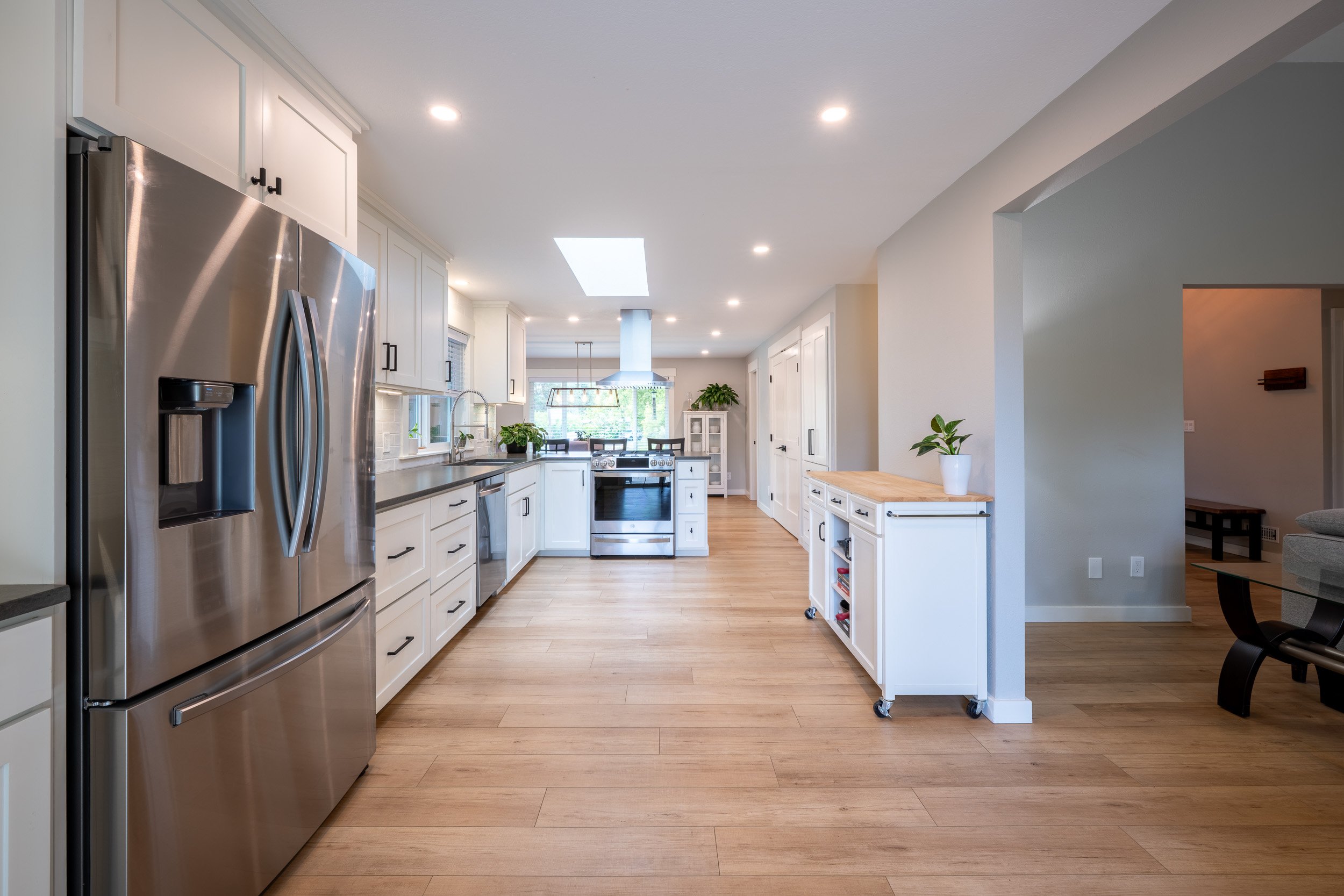 Kitchen with white cabinetry, stainless appliances, and skylights