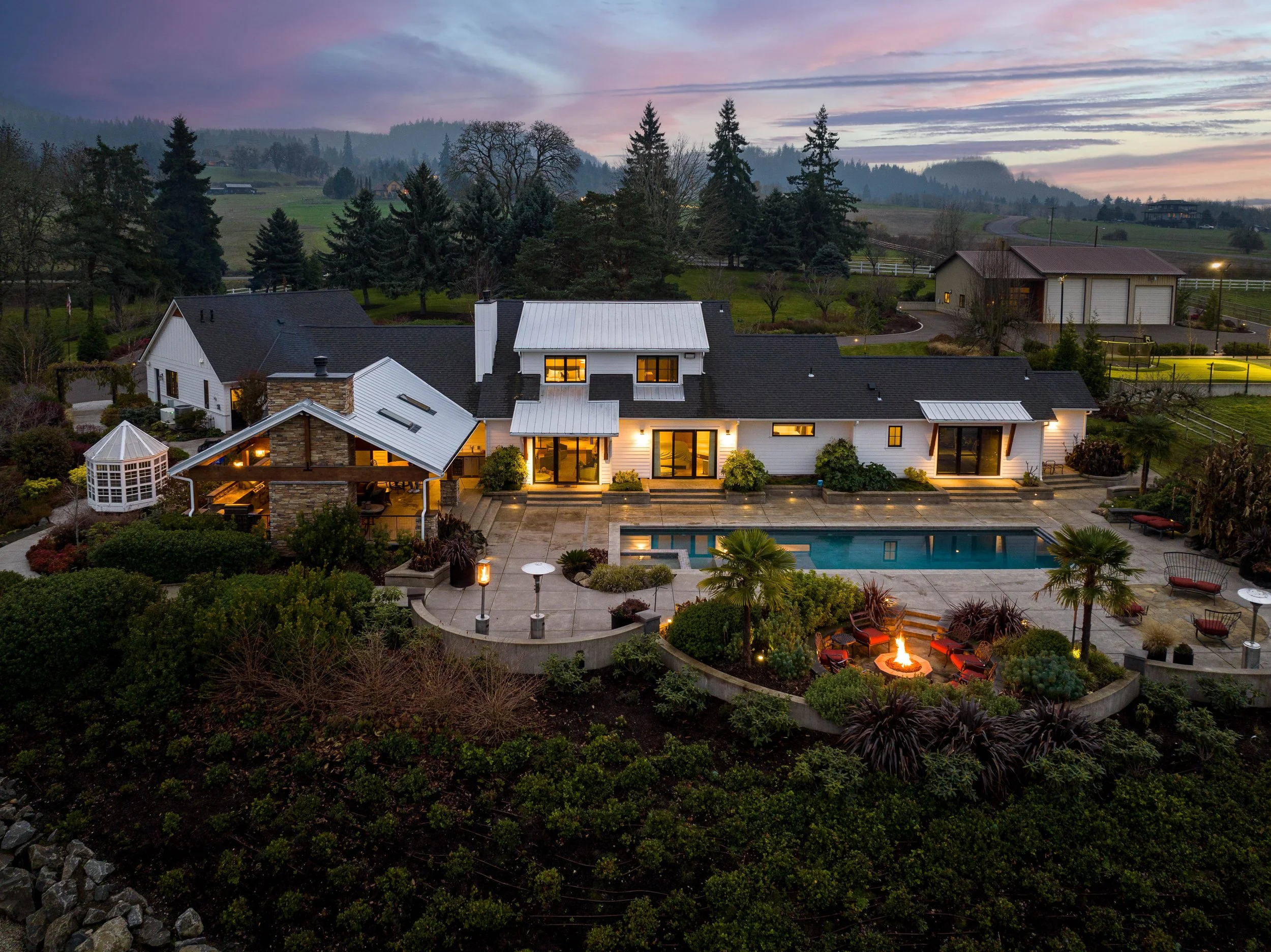 Twilight photo featuring the upscale backyard of a luxury home in Portland Oregon with a pool and elevated landscaping