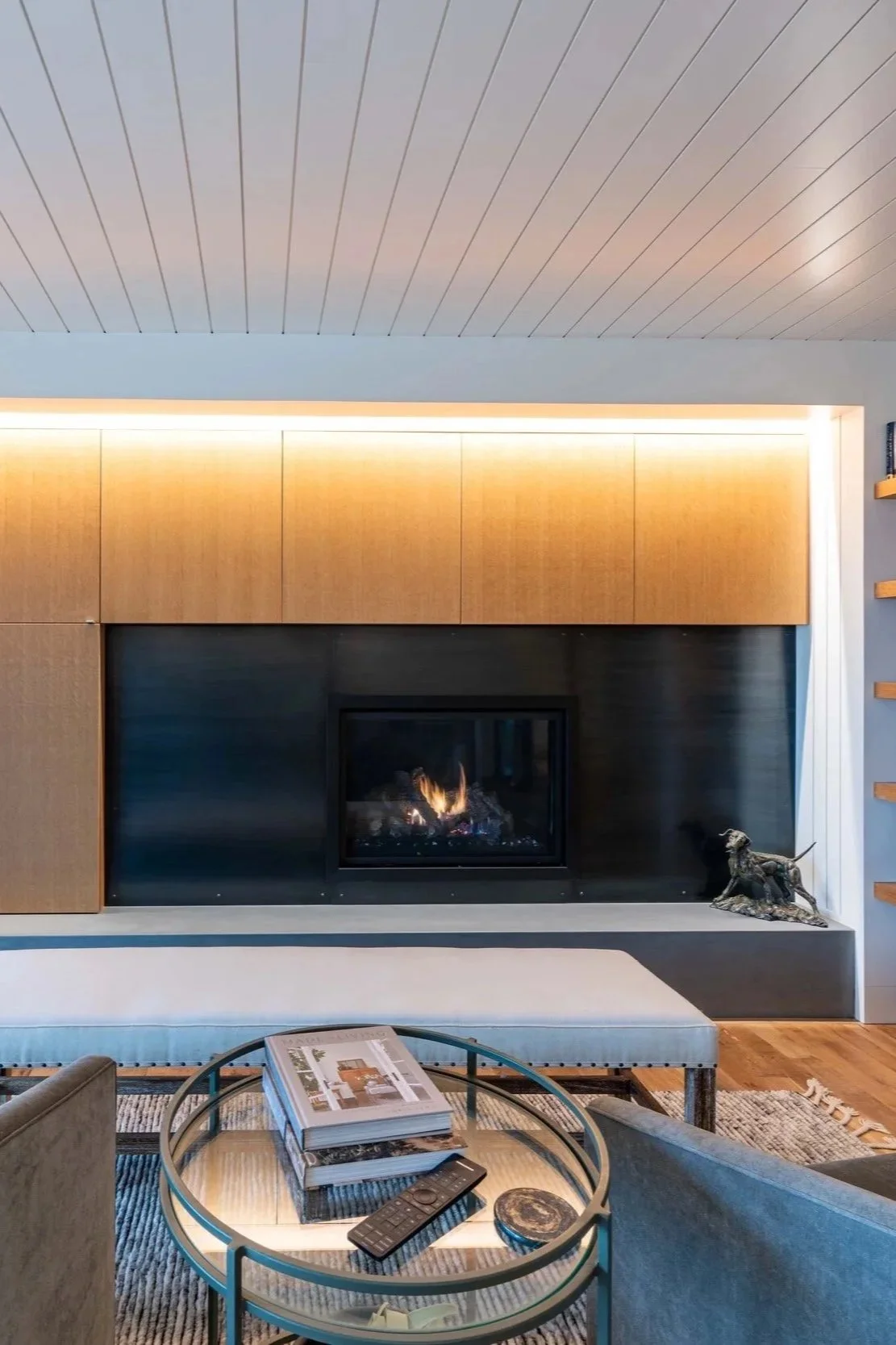 Modern Portland living room with built-in wood cabinetry, linear fireplace, warm accent lighting, floating shelves, and minimalist seating area.
