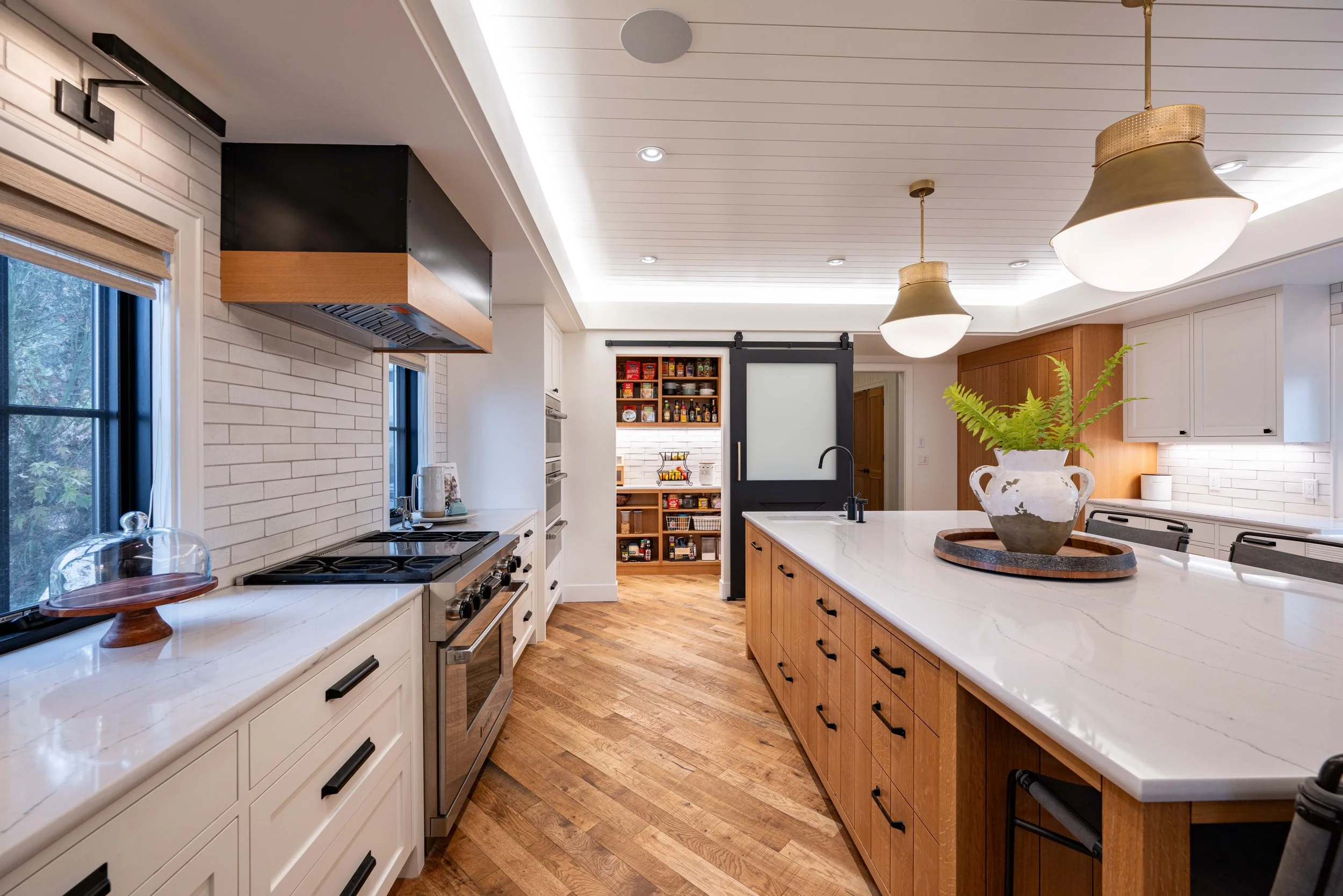 Bright modern kitchen with white cabinetry, wood island, stainless steel range, and warm hardwood floors.