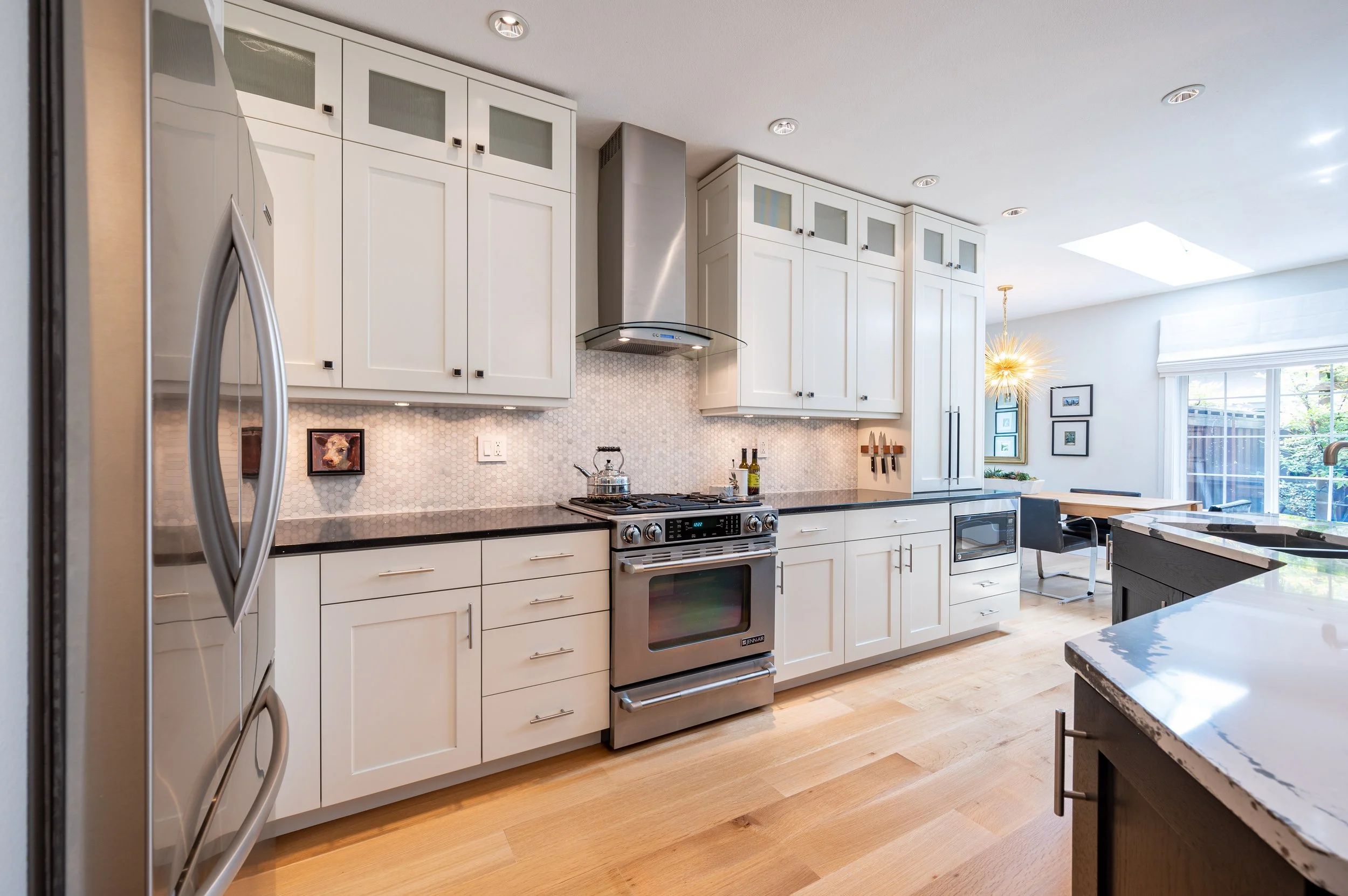 White kitchen with stainless range, tile backsplash, and custom cabinetry