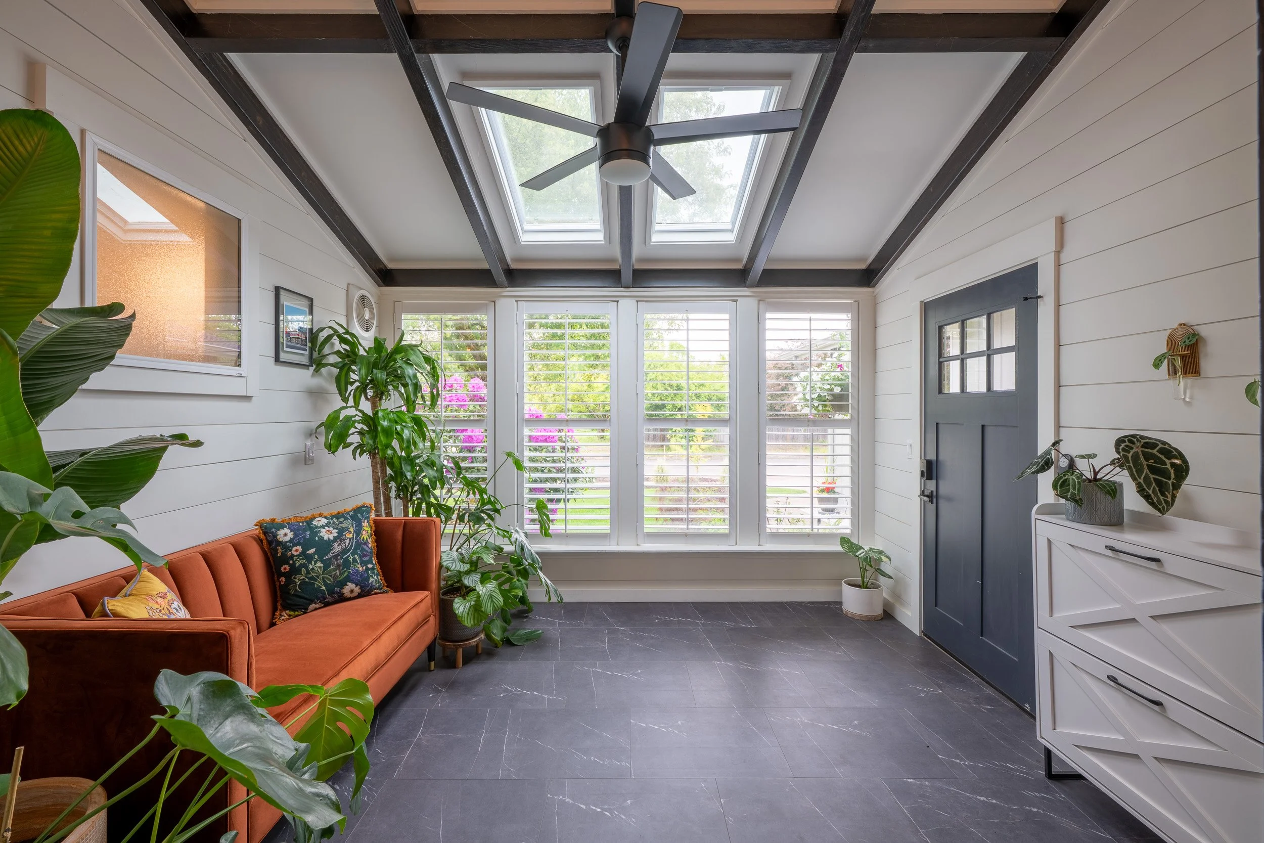 Sunlit modern sunroom with skylights, exposed beams, and indoor plants