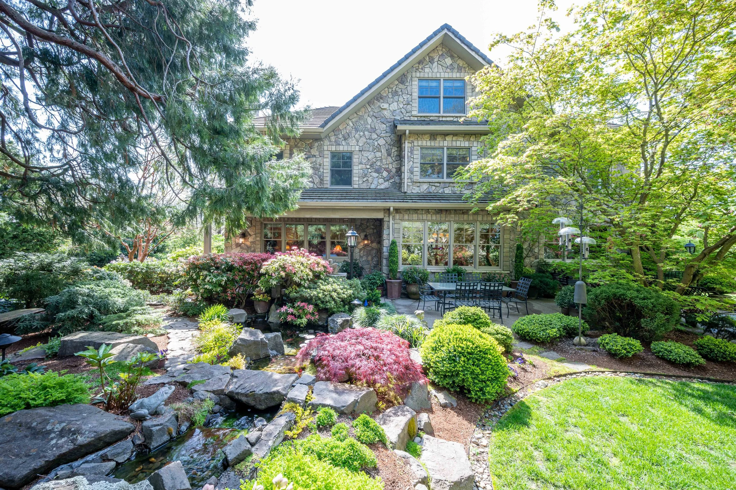Exterior photo of a home in portland with elevated landscaping, mature trees, and a patio