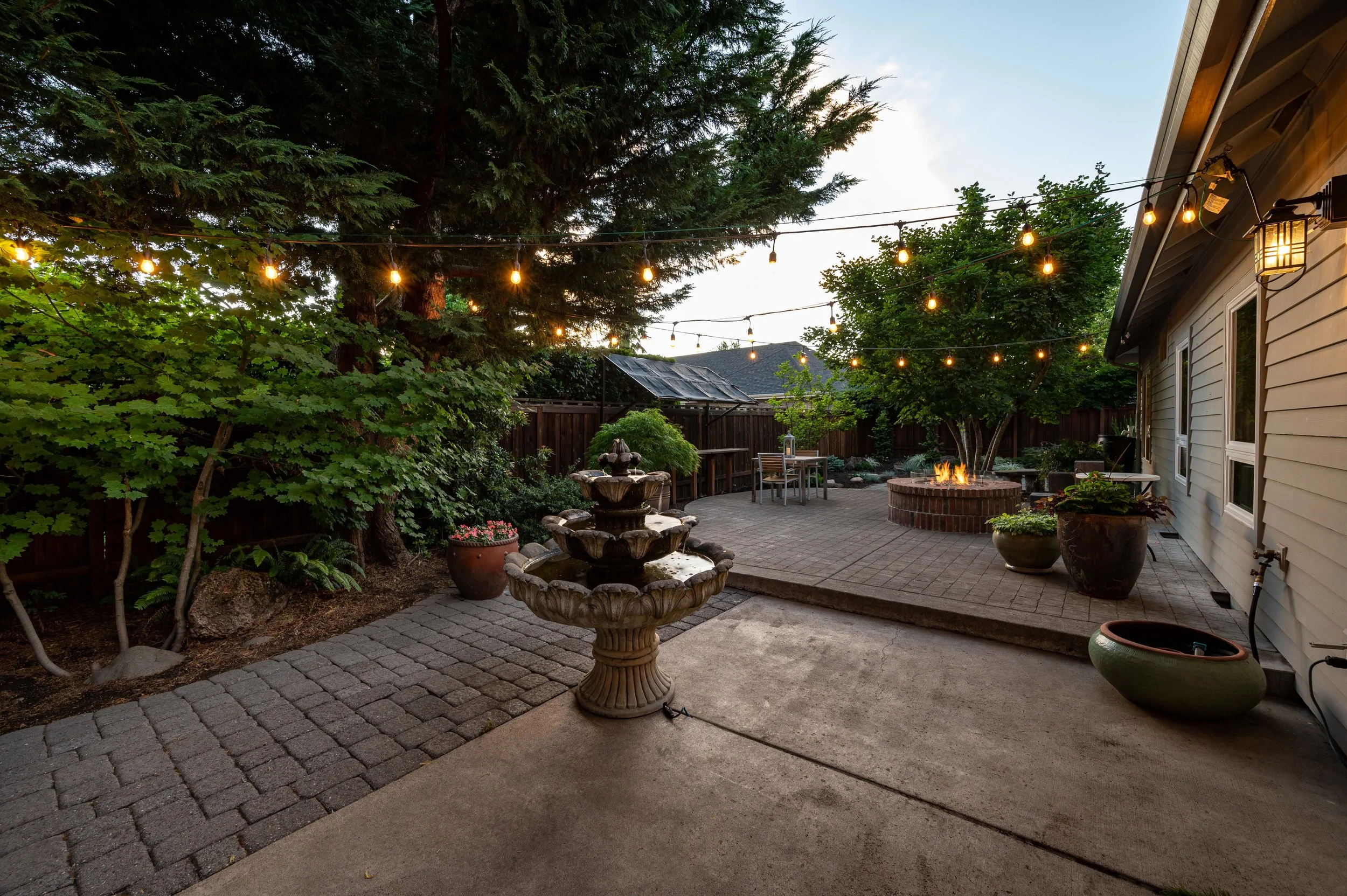 Courtyard patio with string lights, water feature, and evening ambiance