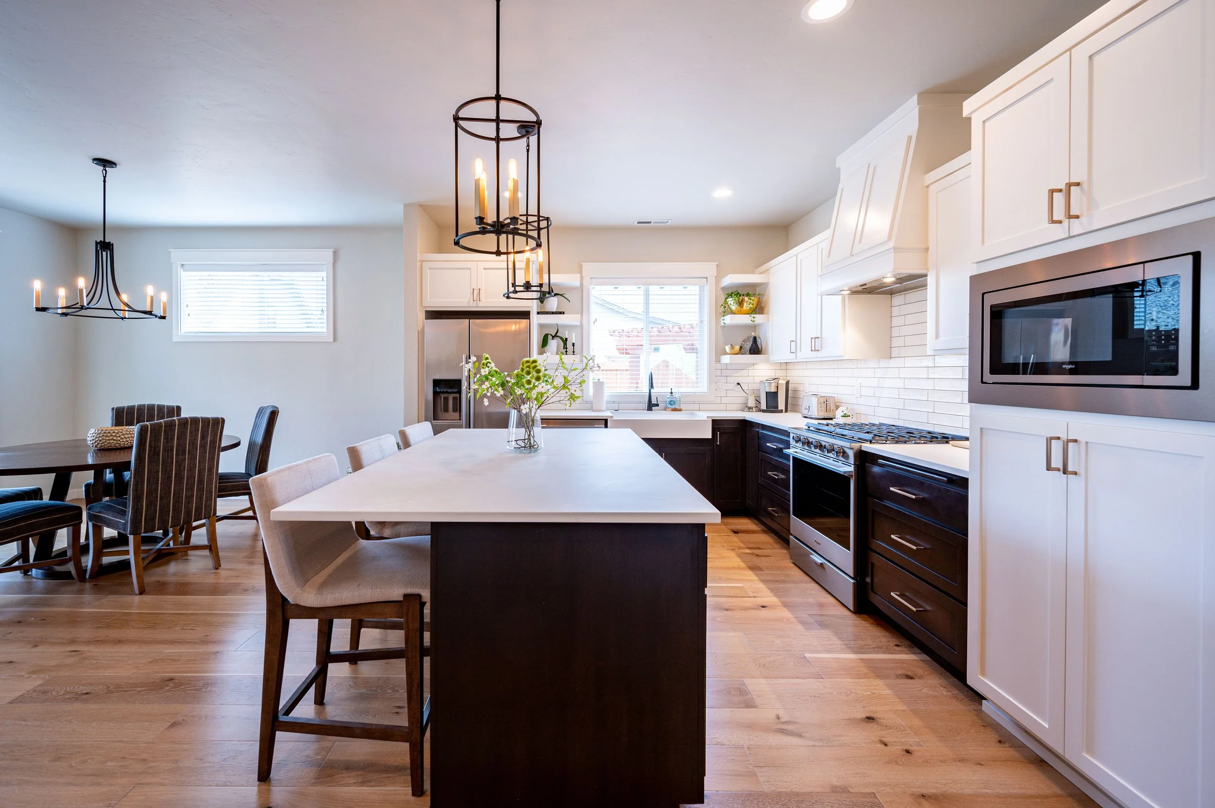 Kitchen with large island, pendant lighting, white cabinetry, and wood flooring