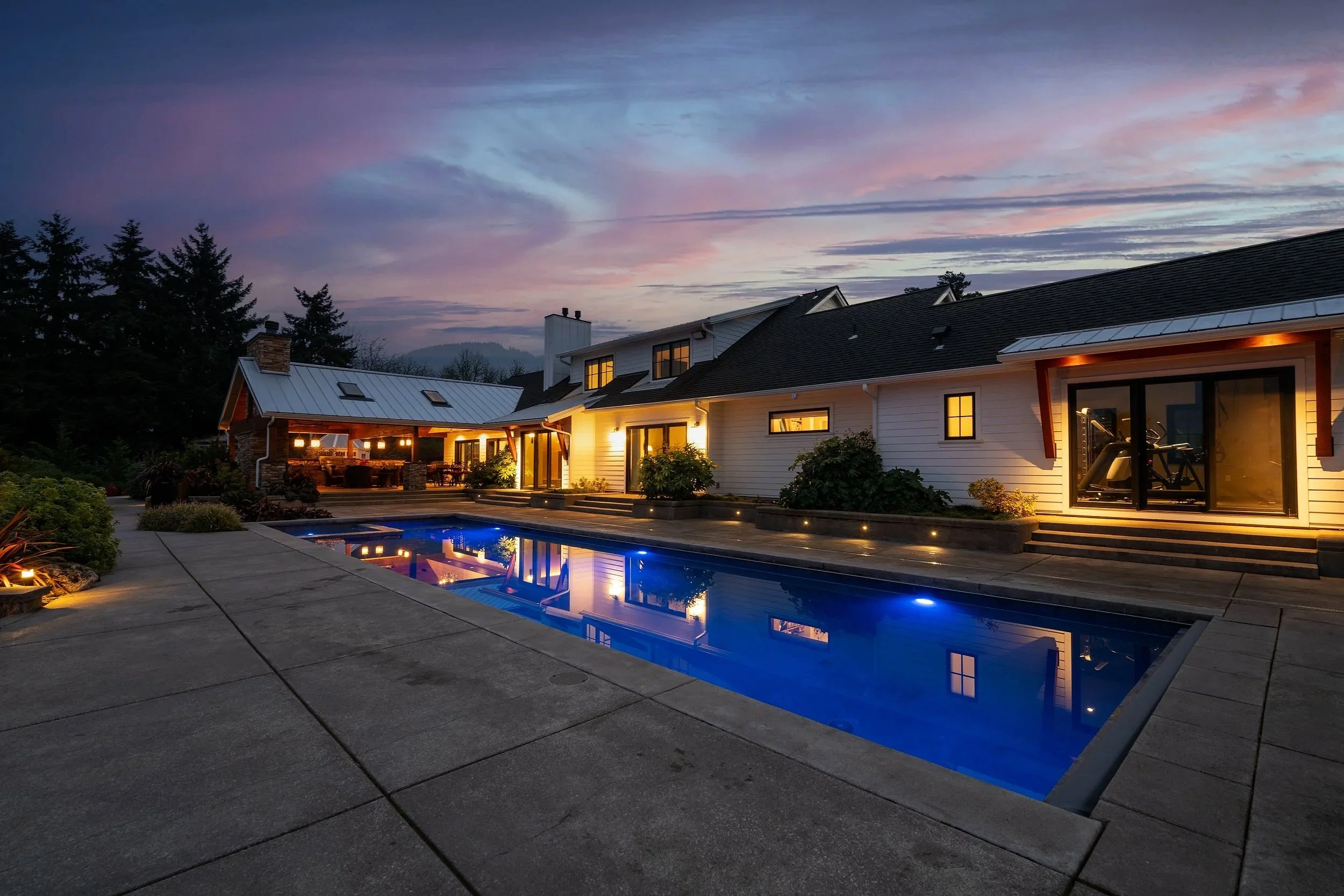 Twilight photo of a luxury home in portland featuring a modern pool and sunset sky