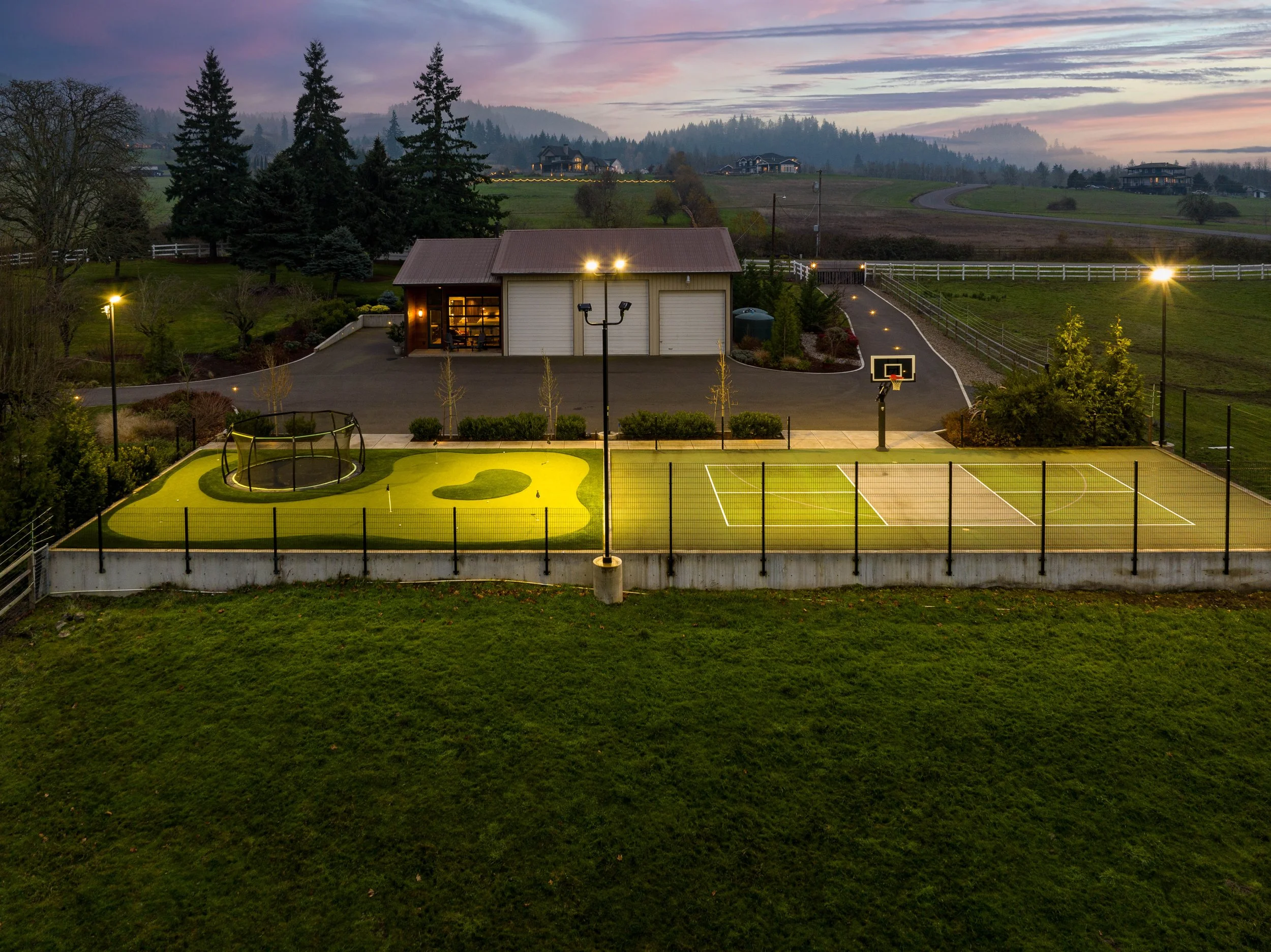 Aerial view of sports court and outbuilding illuminated at night