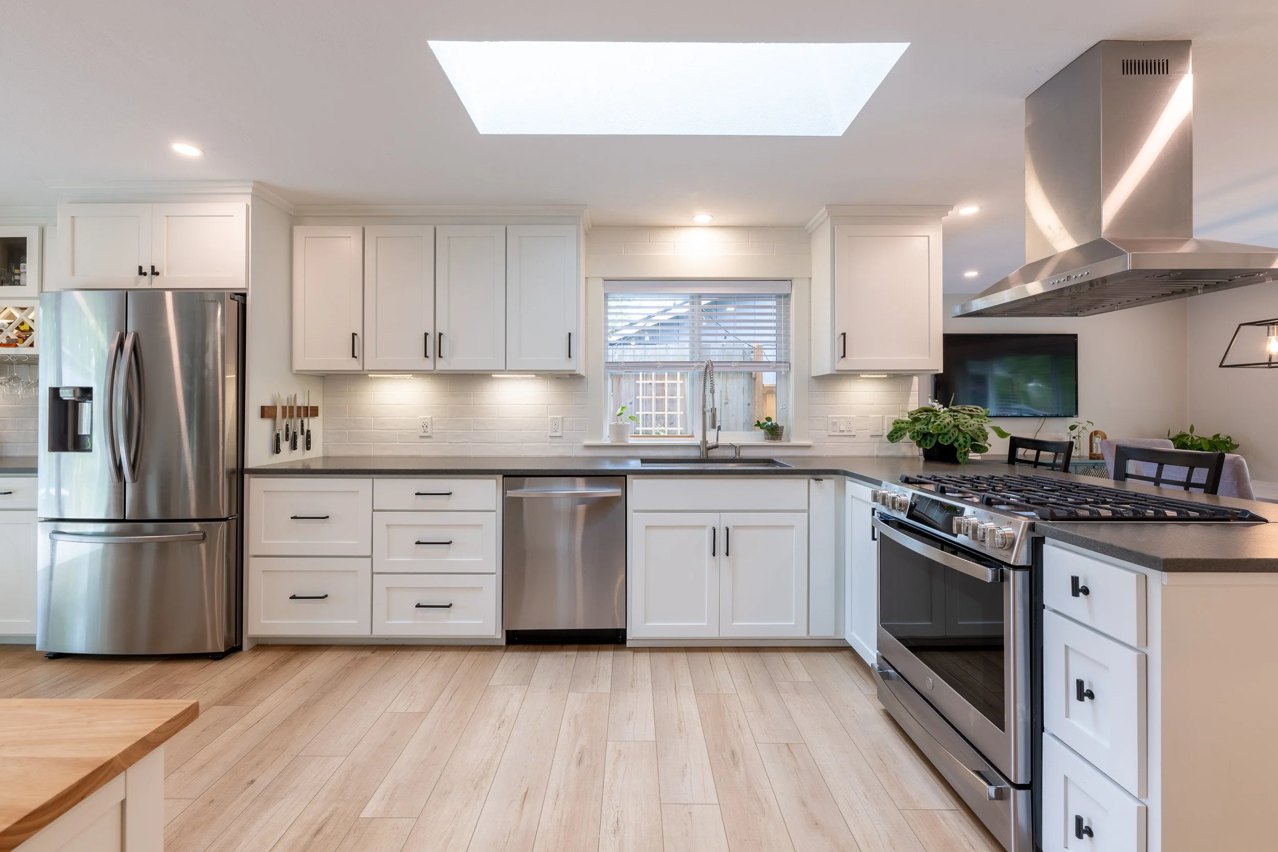 Kitchen with corner layout, white cabinets, and stainless steel appliances